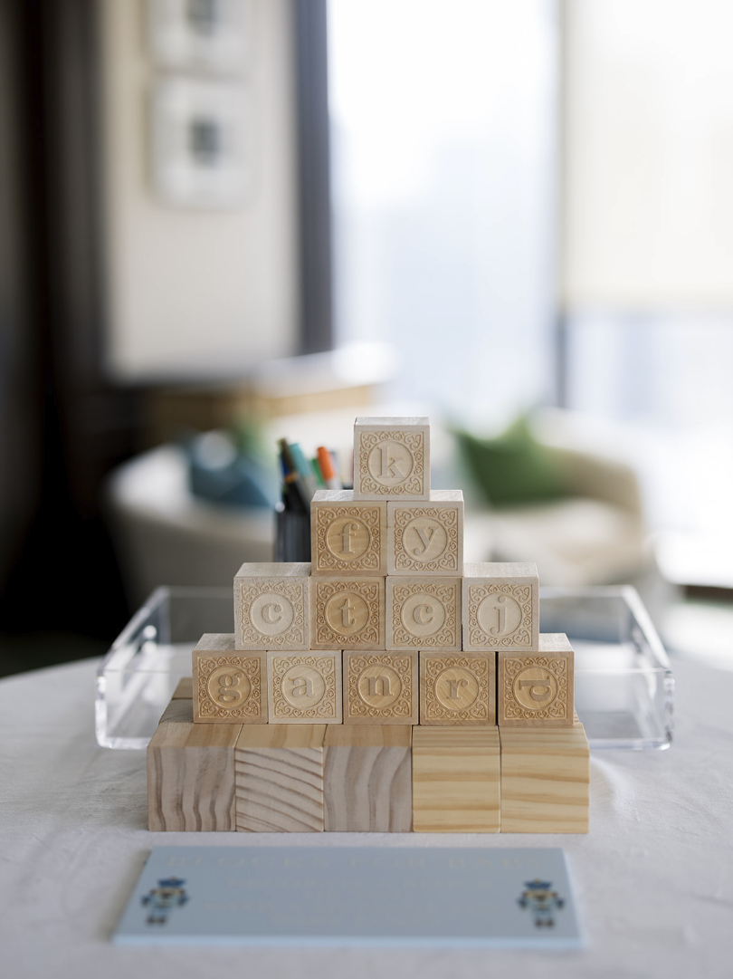 Wooden blocks arranged in a pyramid with the words 'key to our little adventure' spelled out. The blocks are on a table with a blurred background of a room.