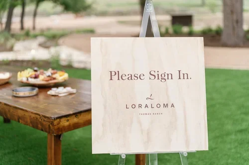 Sign on an easel saying 'Please Sign In' with an outdoor setting in the background.