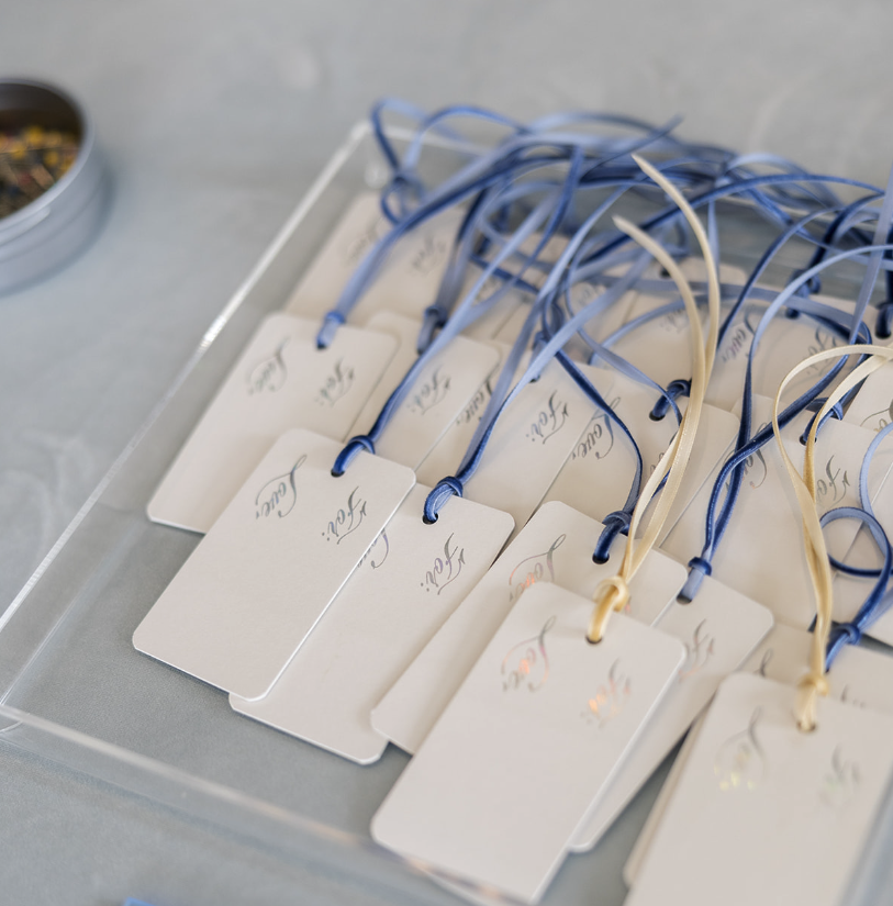 A silver tray with white name tags attached to blue and cream-colored ribbons.