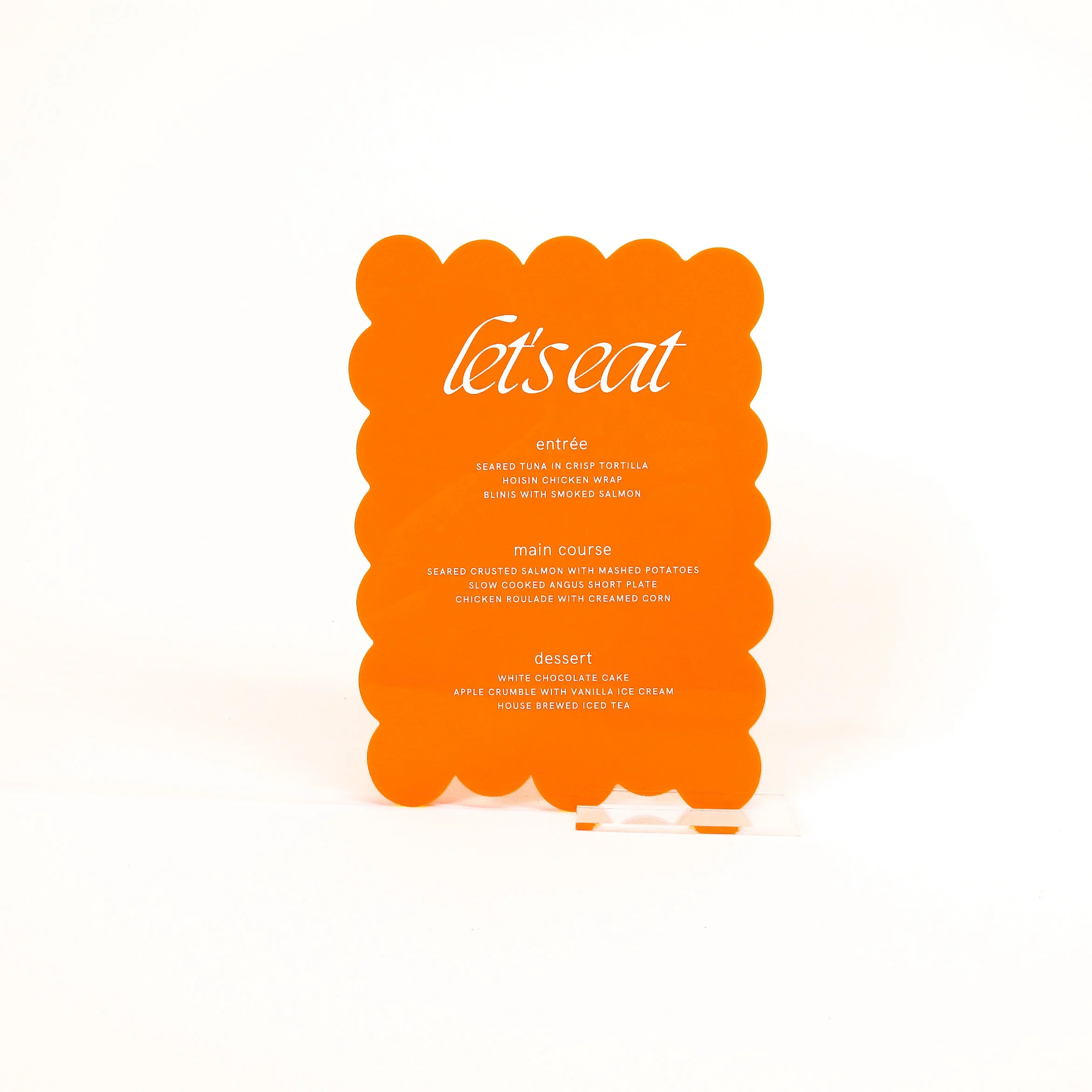 Menu of a restaurant with the title 'let's eat' in orange, featuring sections for entrée, main course, and dessert, with respective dish descriptions.