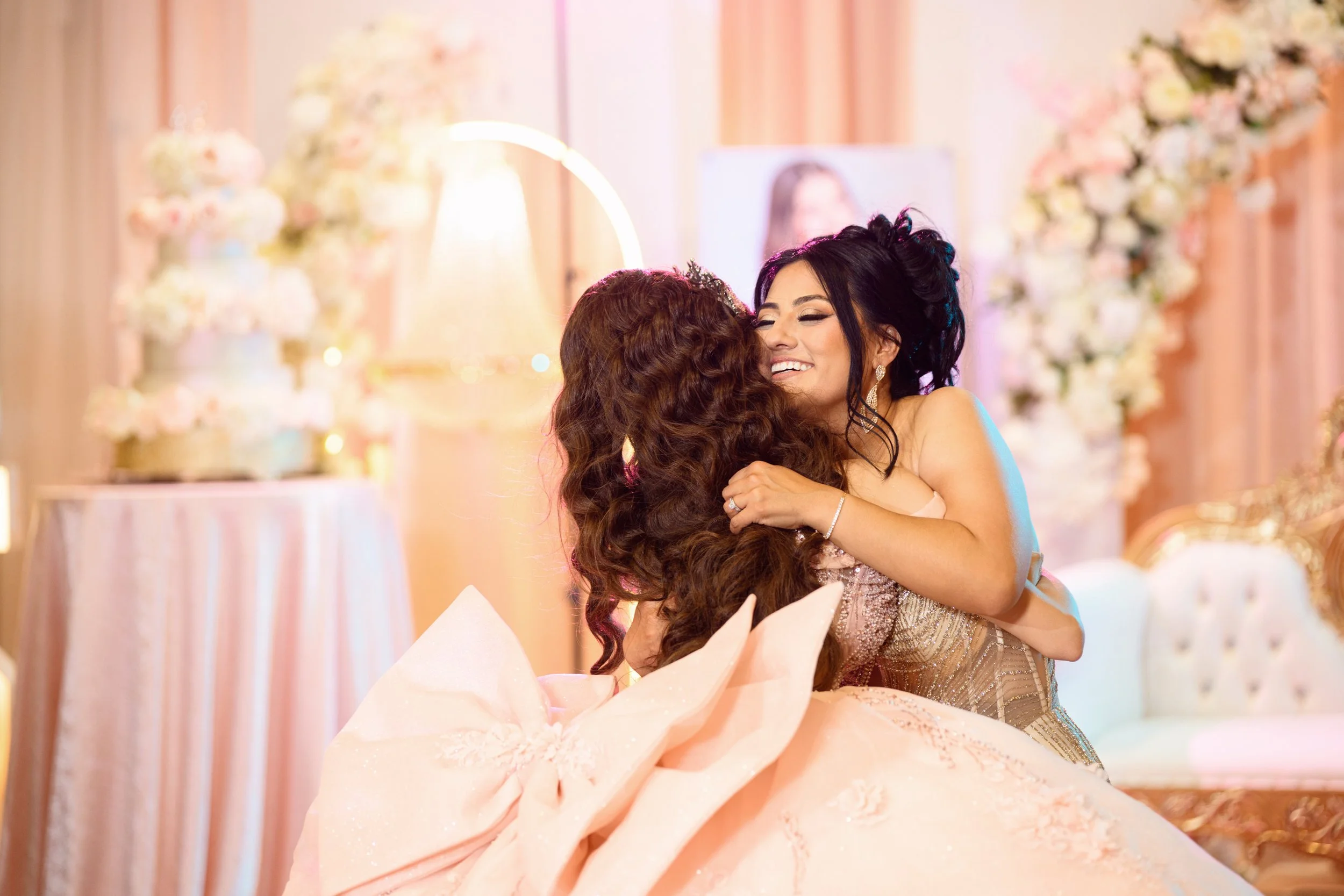 Two people on a decorated dance floor during a quinceañera celebration, holding umbrellas and posing in front of a backdrop with flowers and large number "15".