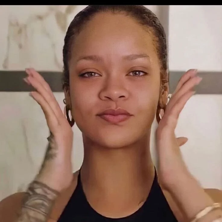 A young woman adjusting her hair, looking directly at the camera with a neutral expression.