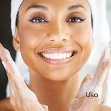 Close-up of a smiling woman with clear skin, holding soap or cleanser in her hands, indicating skincare or personal hygiene.