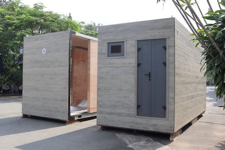 Two small wooden structures outdoors, one with an open door and the other with a closed door and a small window.