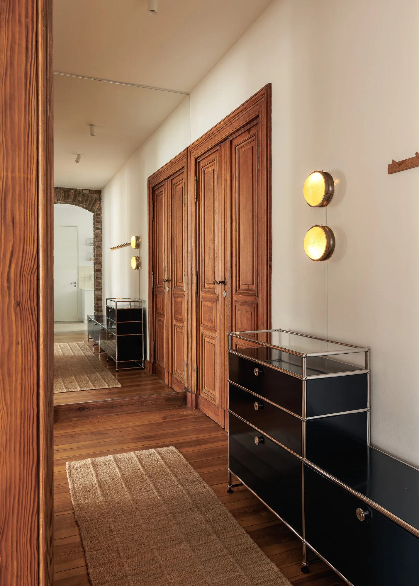 Architectural view of a Berlin Altbau hallway featuring the industrial Parentesi lamp by Flos and large historical windows, interior design and architectural photography by Alessandra Brescia Photography