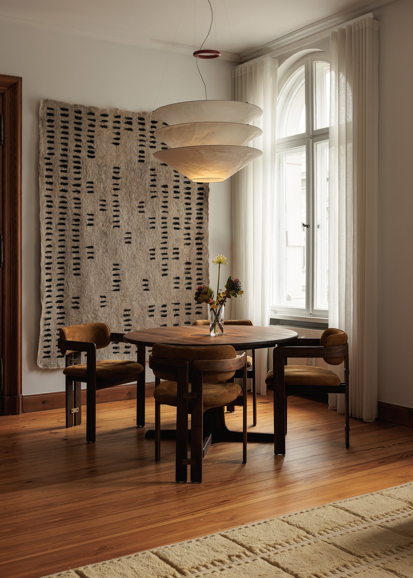 Bright open-plan dining area featuring black Thonet 209 chairs around a minimalist wood table in a light-filled Berlin apartment, interior design and architectural photography by Alessandra Brescia Photography