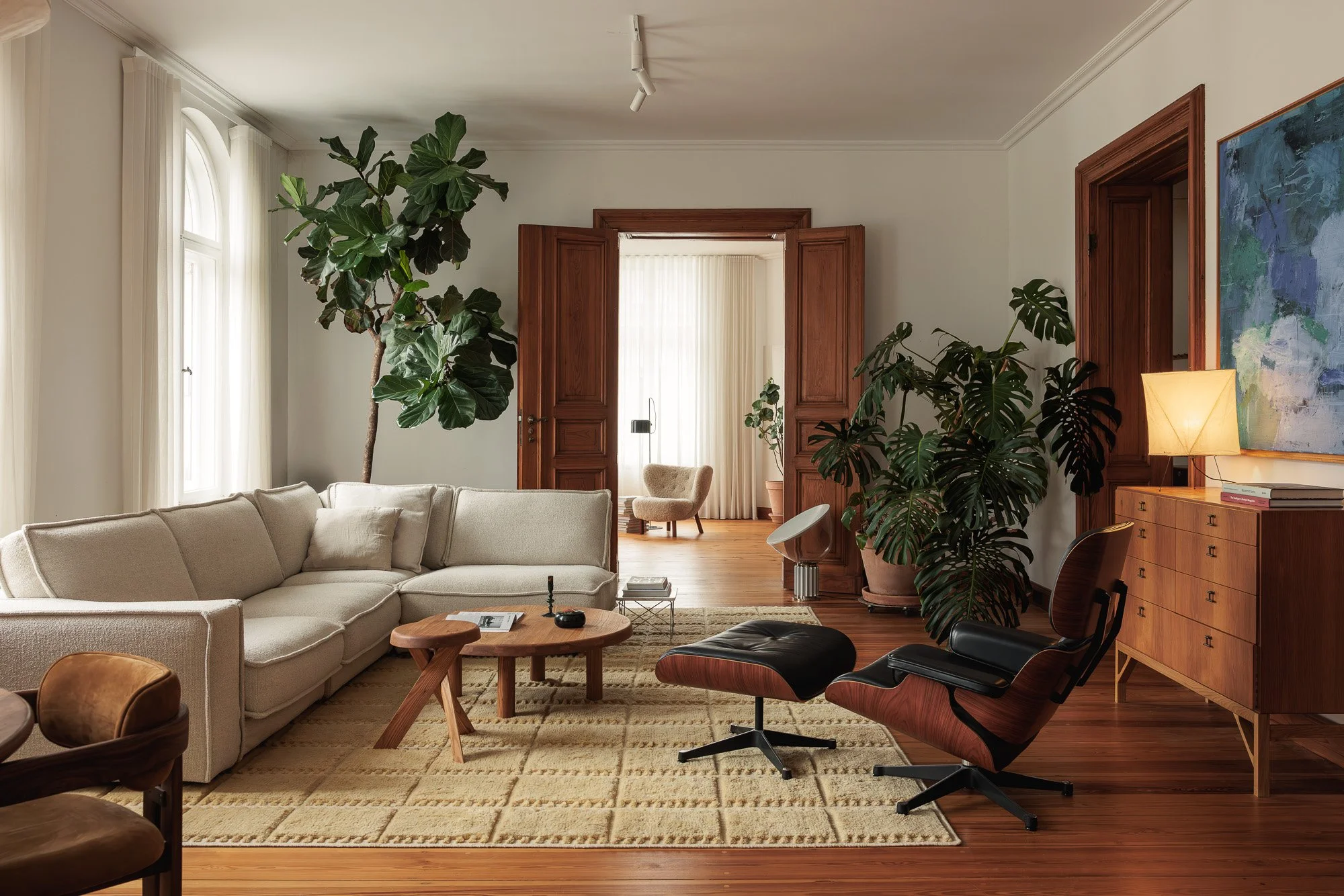 Spacious minimalist living room in a Berlin Altbau featuring the iconic cream Ligne Roset Togo sofa on herringbone parquet floors, interior design and architectural photography by Alessandra Brescia Photography