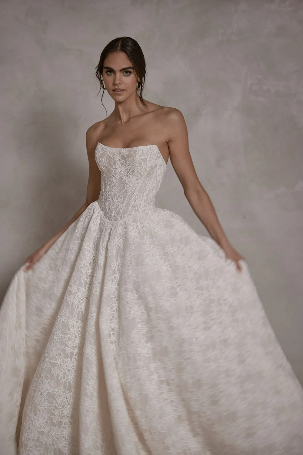 Elysia wedding gown featuring a structured boned corset with built-in cups, corded Alençon lace with subtle micro sequins, a lace-up back, a basque waist ballgown skirt, detachable crinoline petticoat for added volume, and a sweeping train.