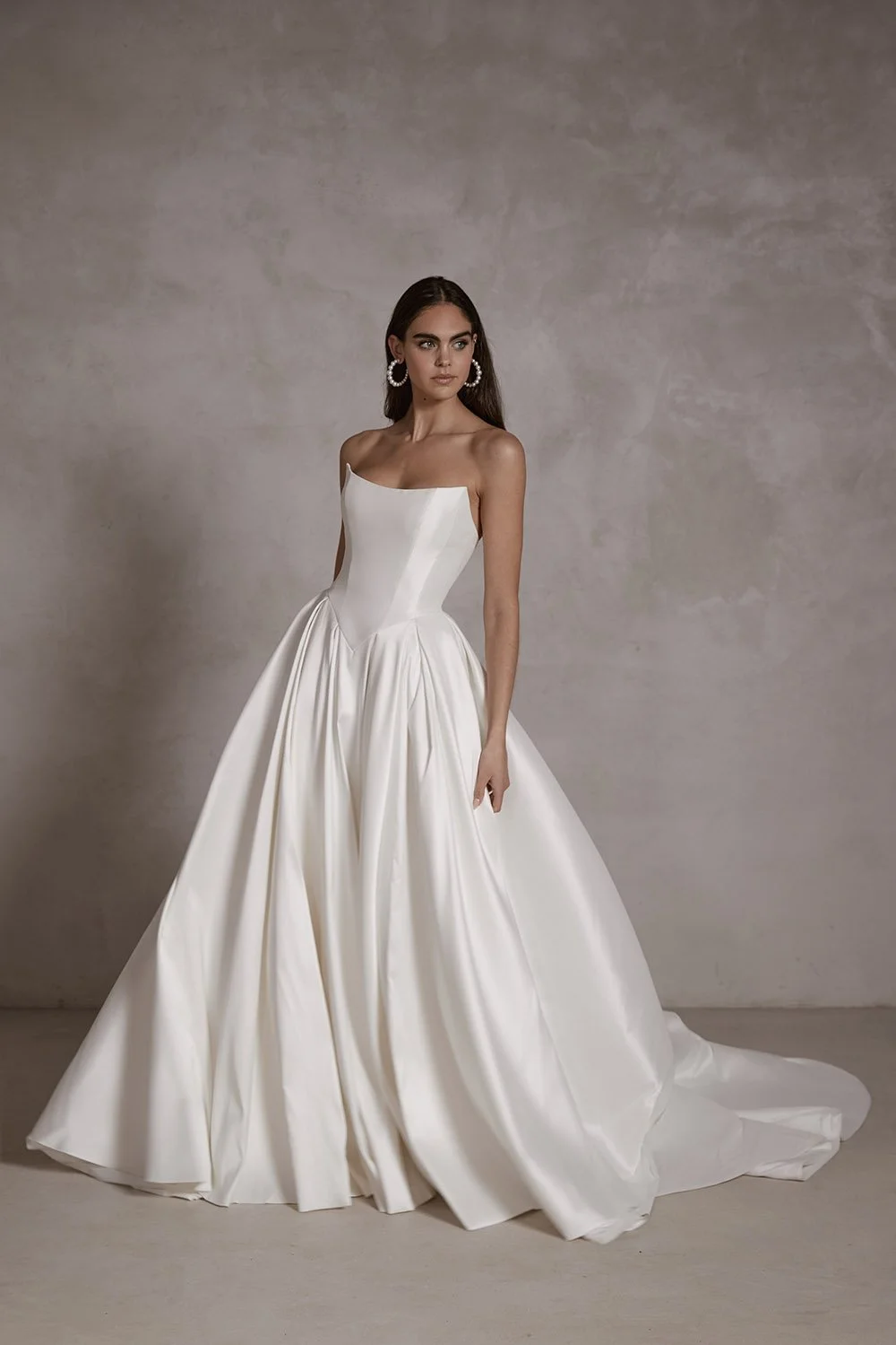 Isolde wedding gown featuring a structured stretch Mikado corset with built-in cups, a basque waist, elegant box-pleated skirt, detachable petticoat for added volume, and a sweeping train with covered buttons.