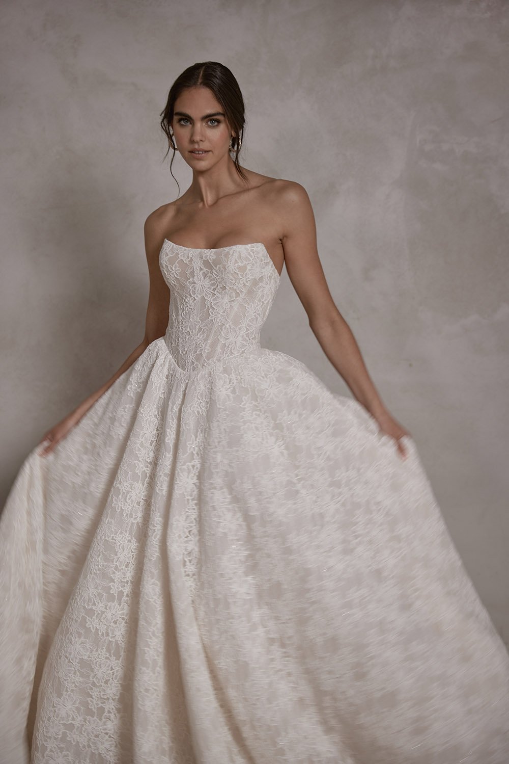 Elysia wedding gown featuring a structured boned corset with built-in cups, corded Alençon lace with subtle micro sequins, a lace-up back, a basque waist ballgown skirt, detachable crinoline petticoat for added volume, and a sweeping train.