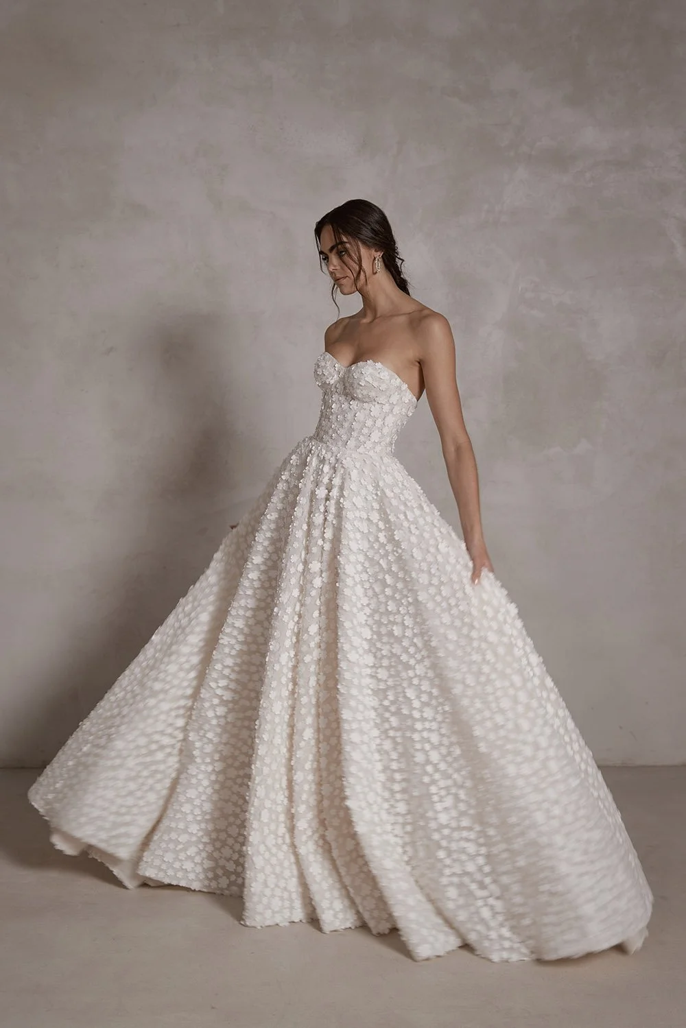 Raphaella wedding gown featuring a boned corset with built-in push-up cups, 3D floral lace over Chantilly lace and tulle, a natural waist ballgown skirt, detachable crinoline petticoat for added volume, and an optional horsehair hem.