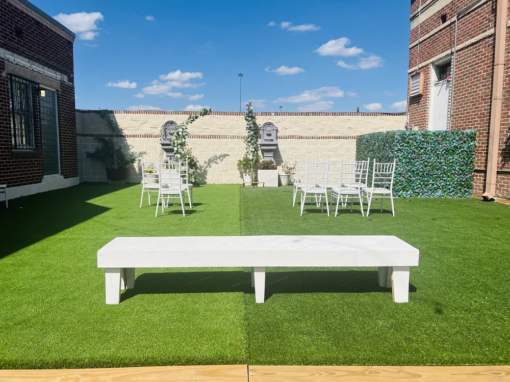 An outdoor wedding ceremony set up in the courtyard with white chairs and a stone fountain