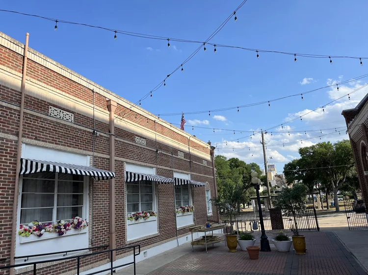 The brick front of the Italian Hall with striped awnings and window boxes