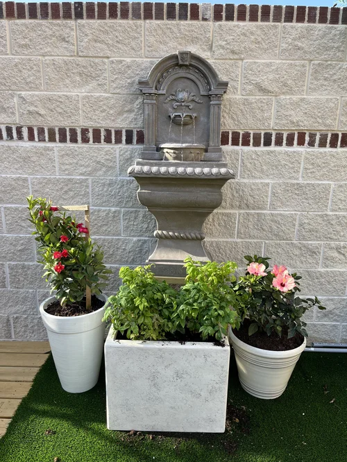 The courtyard's stone wall fountain with flowering plants