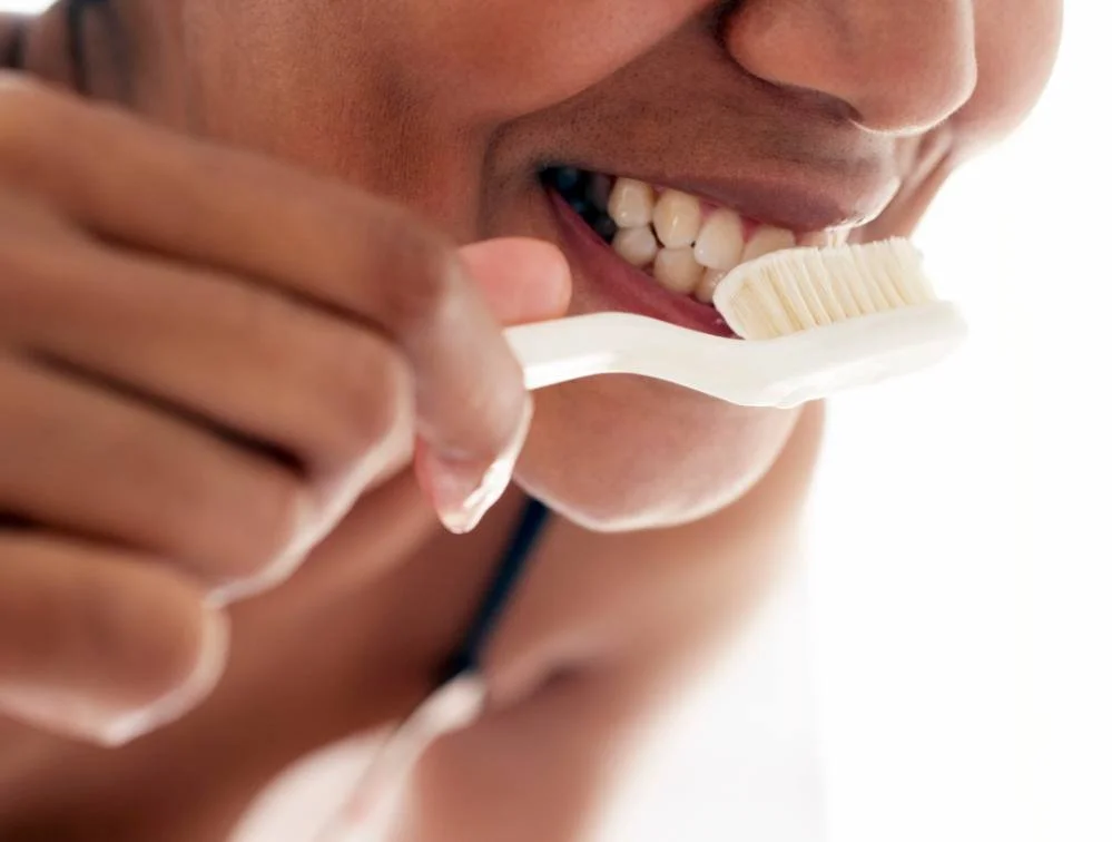 Close-up of a person brushing their front teeth with a white toothbrush