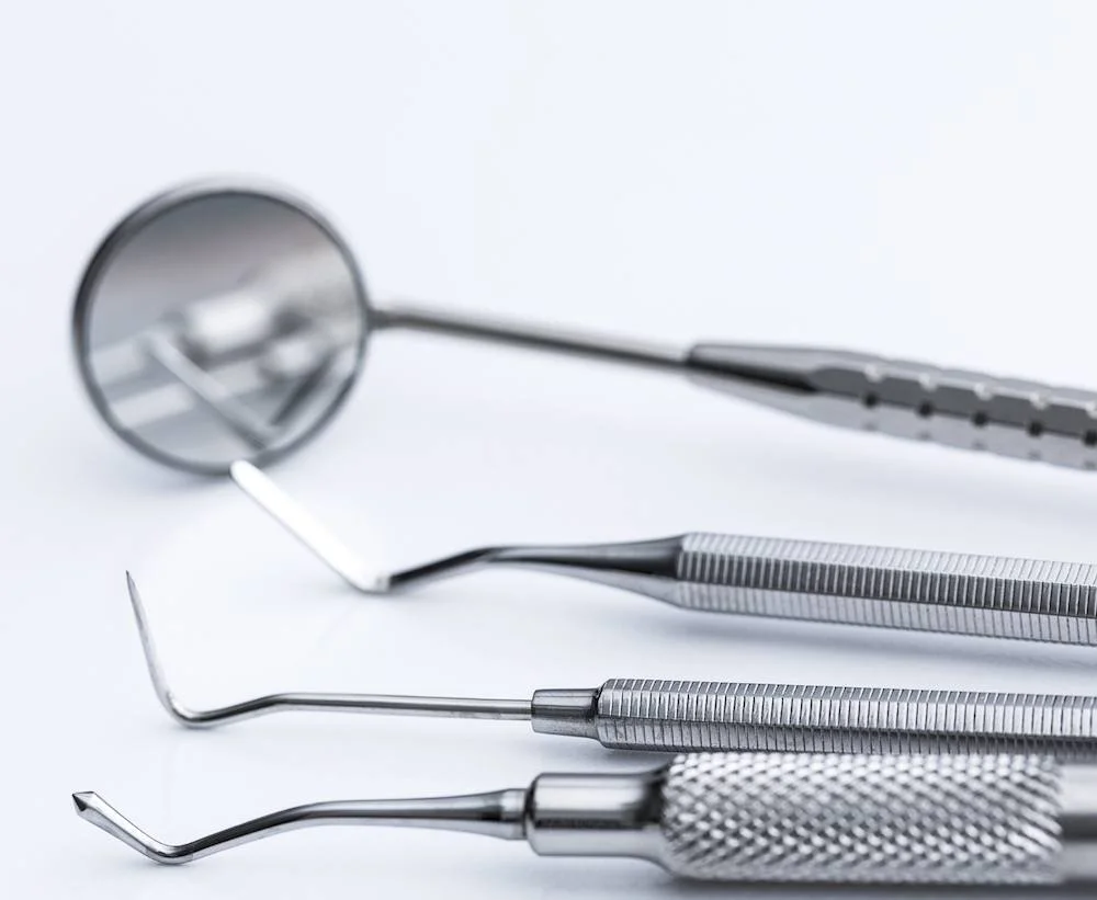 Dental mirror, probe and scaler arranged on a white surface