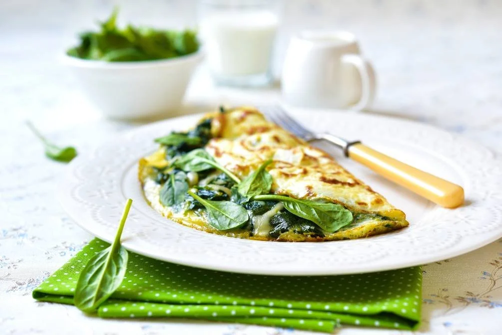 Folded spinach omelette on a white plate with a green napkin