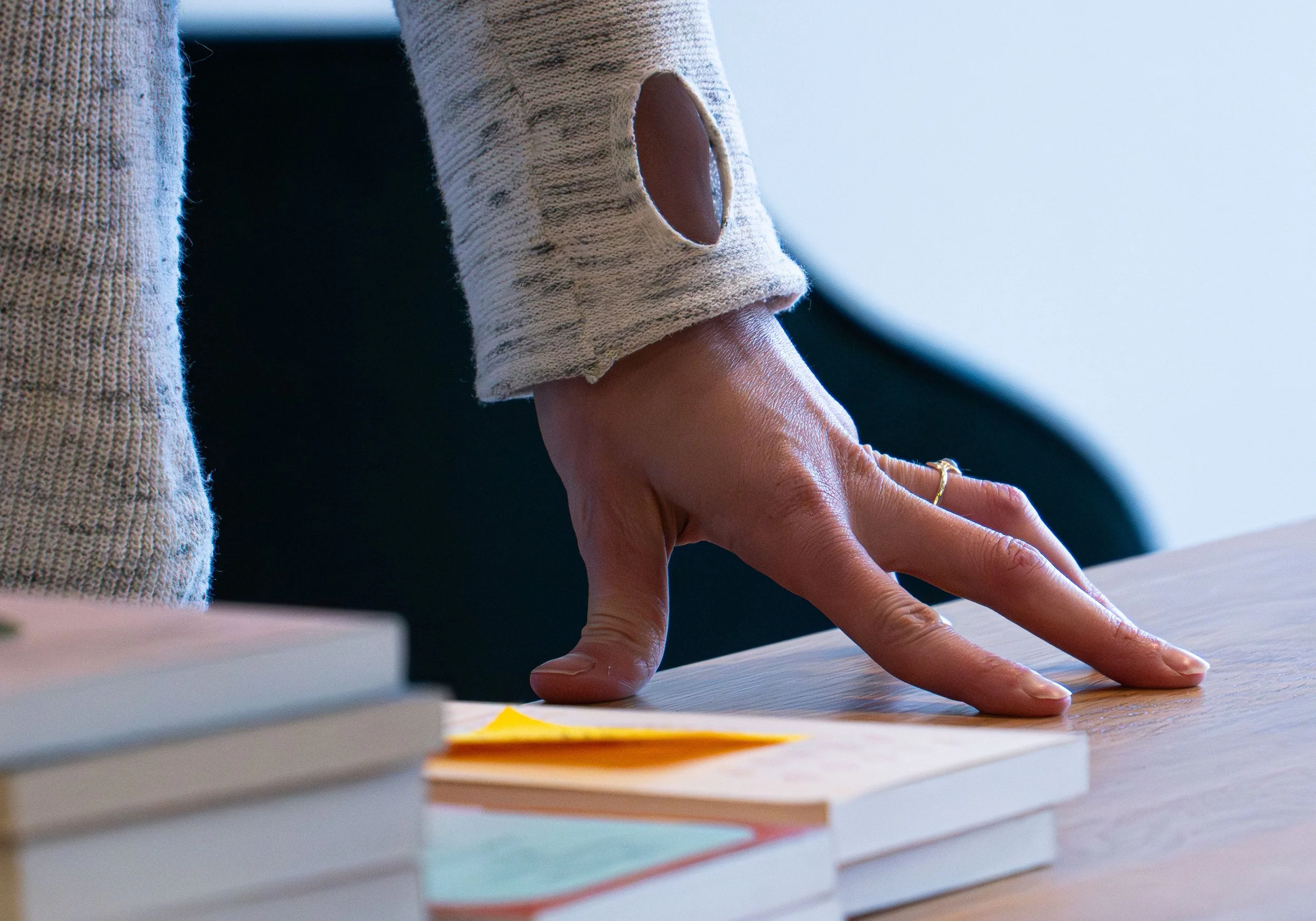 Christine Peffer, resting her hand on a book display while trying to map out what books should go on this table for their Kinshop event prep at A Novel Concept on October 24th, 2025 in Lansing Mich.
