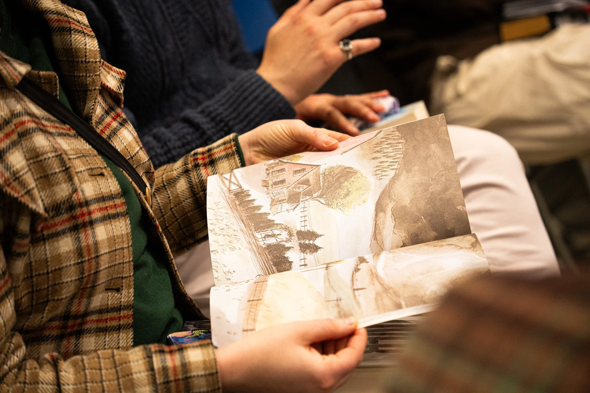 The entire club passing around a book one of the members brought from their childhood and admiring the illustrations during the November Book Club meeting on November 20th, 2025 in Lansing, Mich.