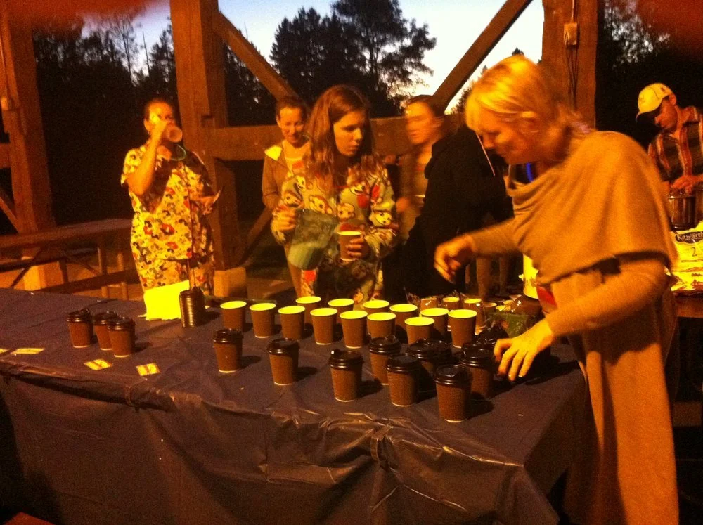 People preparing drinks on a table at an outdoor gathering during sunset.