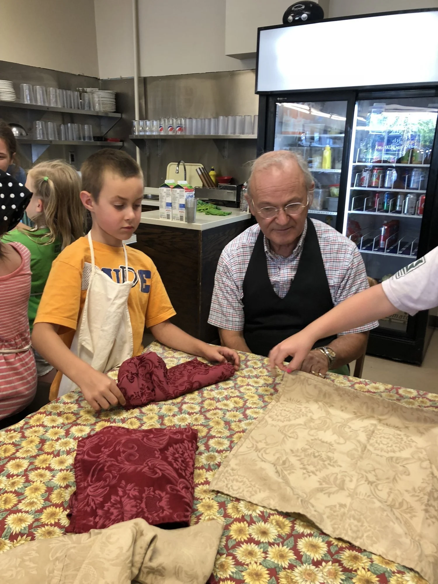 Star Camper Benson learns to fold fancy napkins.