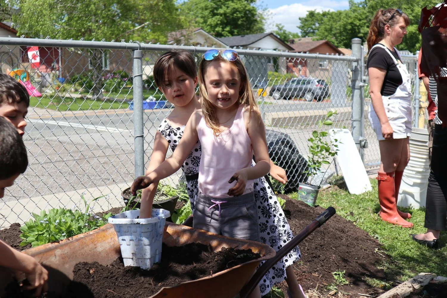 Kids in dirt wheelbarrow