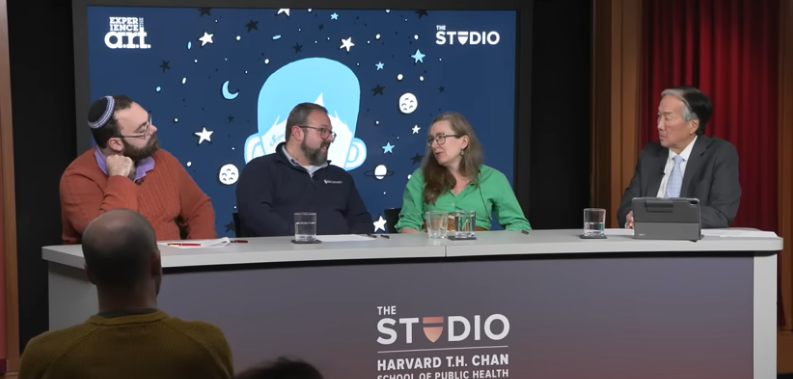 four adults seated behind a desk
