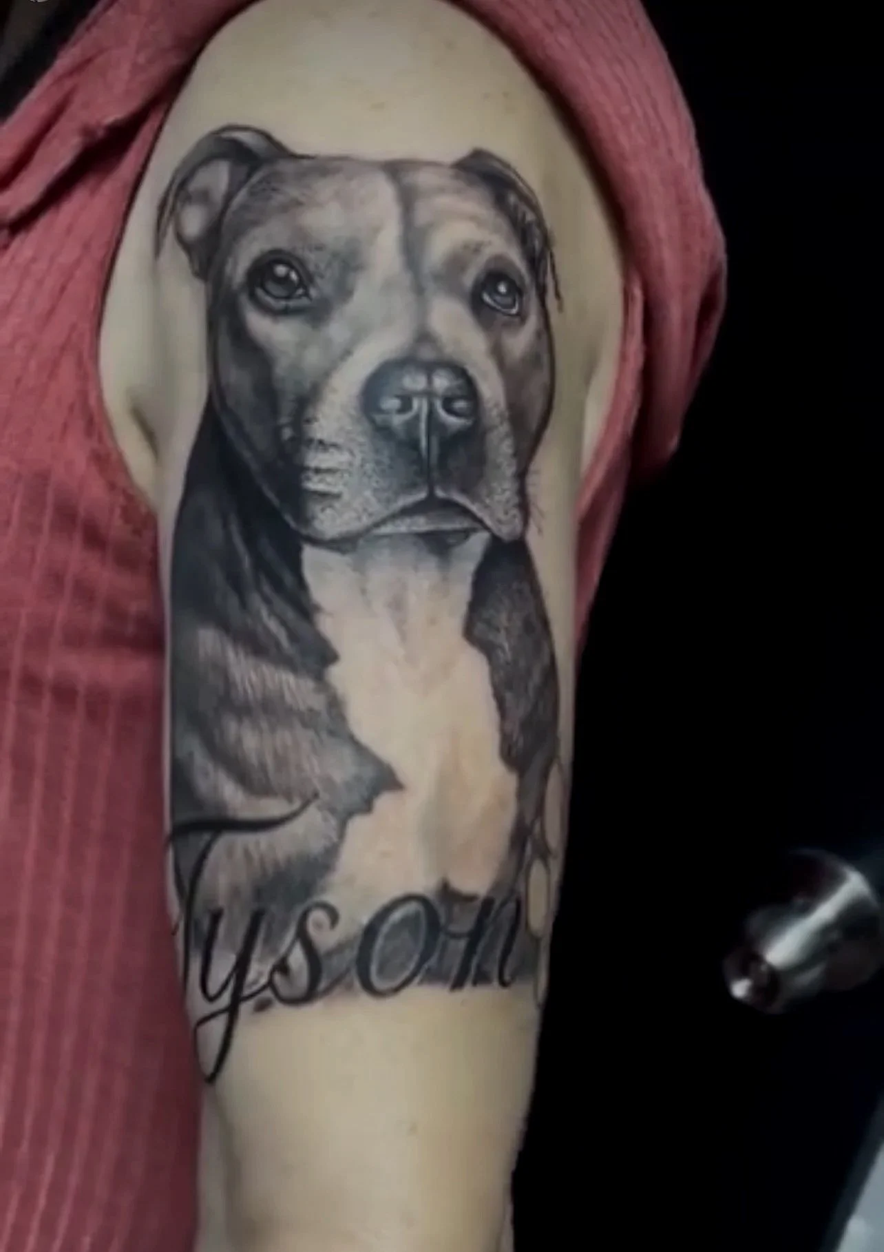 Tattoo of a realistic dog's face on a person's upper arm, with the words "Yes Oh" written beneath.