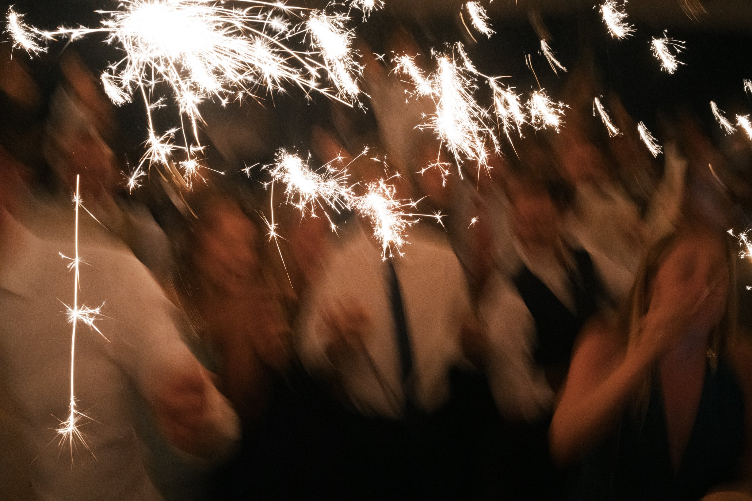 People celebrating with sparklers during a New Year's celebration or party at night.