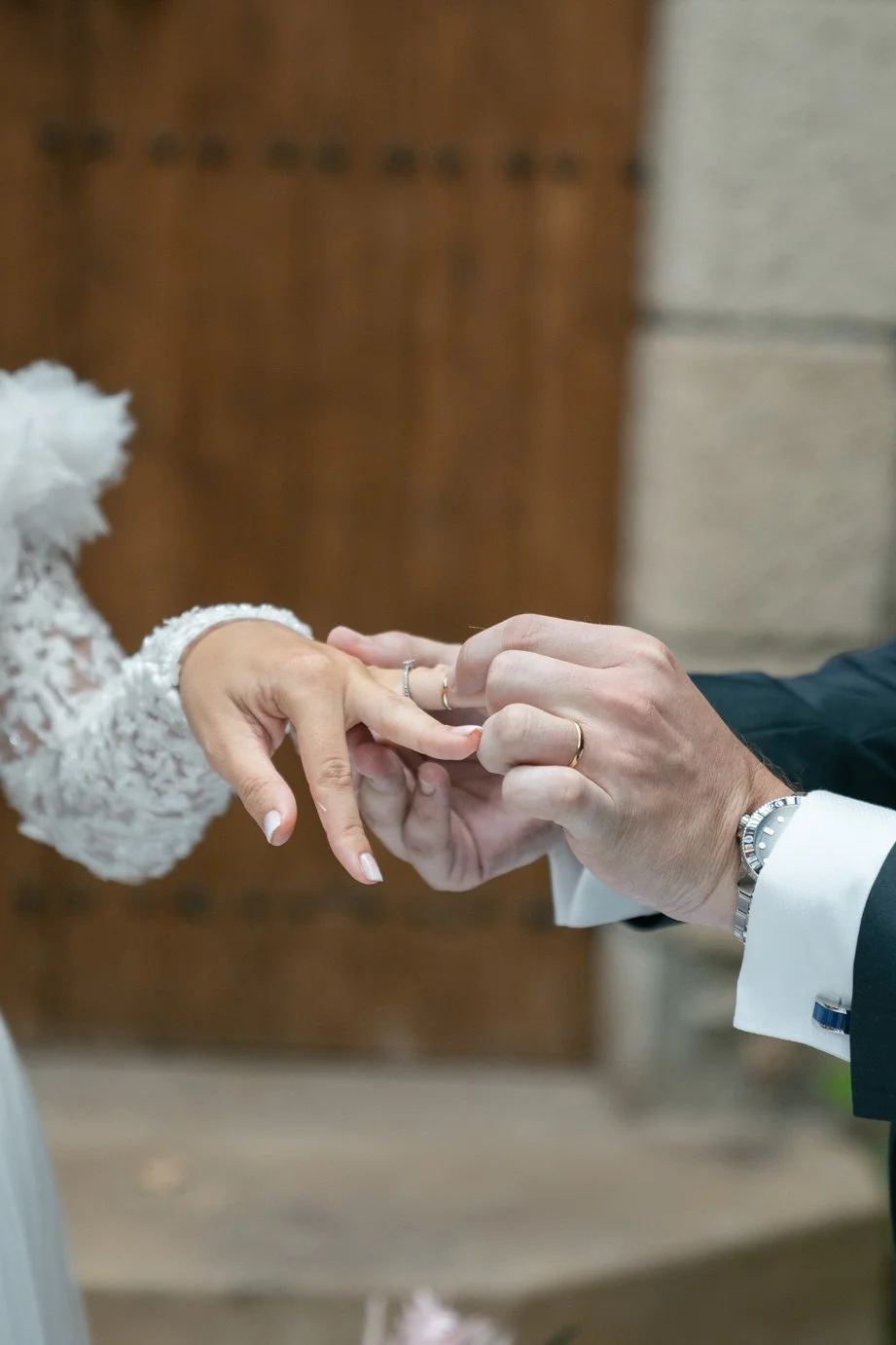 Close-up of a couple exchanging wedding rings during a wedding ceremony, with the woman's hand extended and the man's hand placing the ring on her finger.
