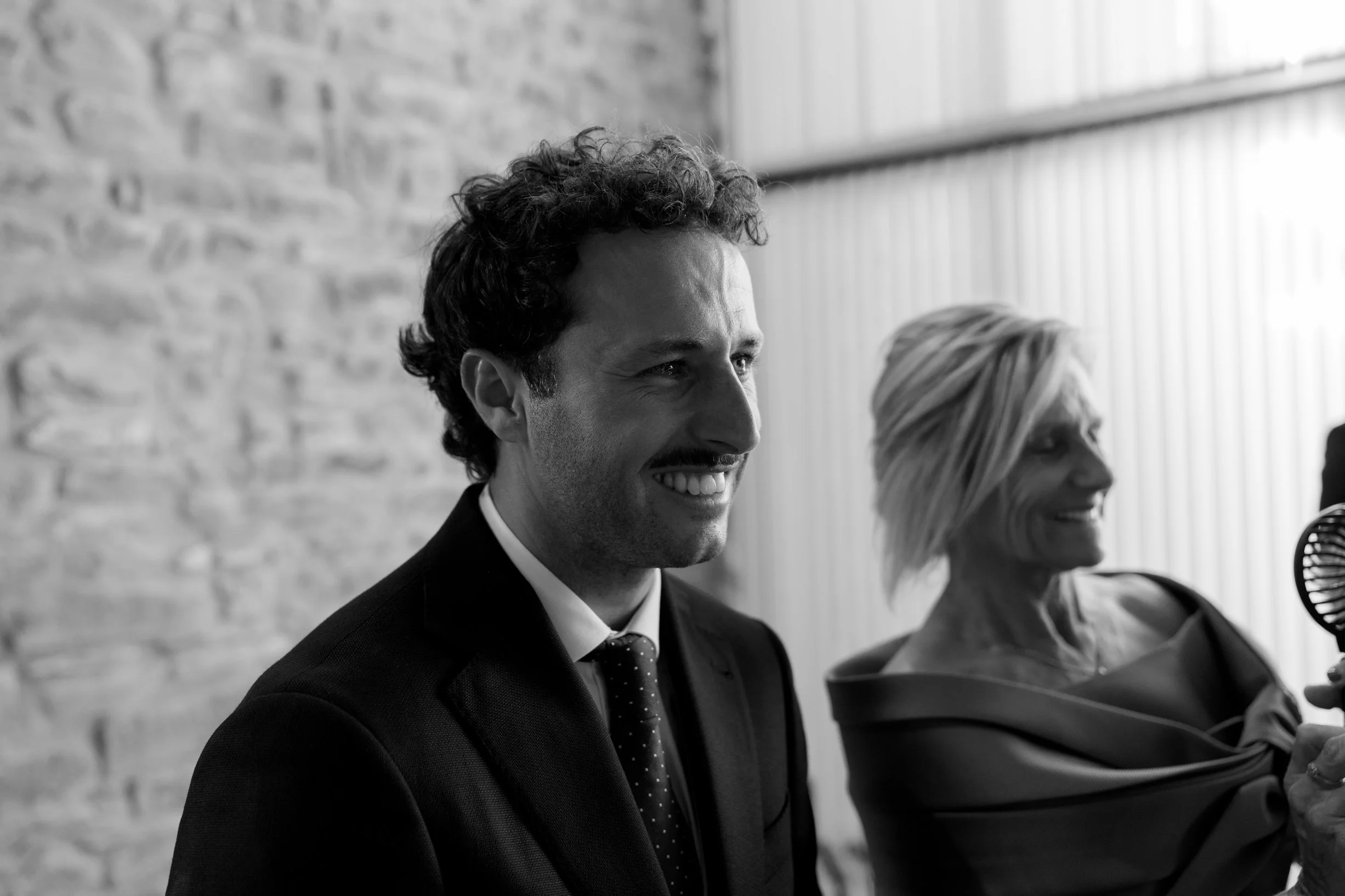 Smiling man in suit and woman with short blonde hair at an indoor event.