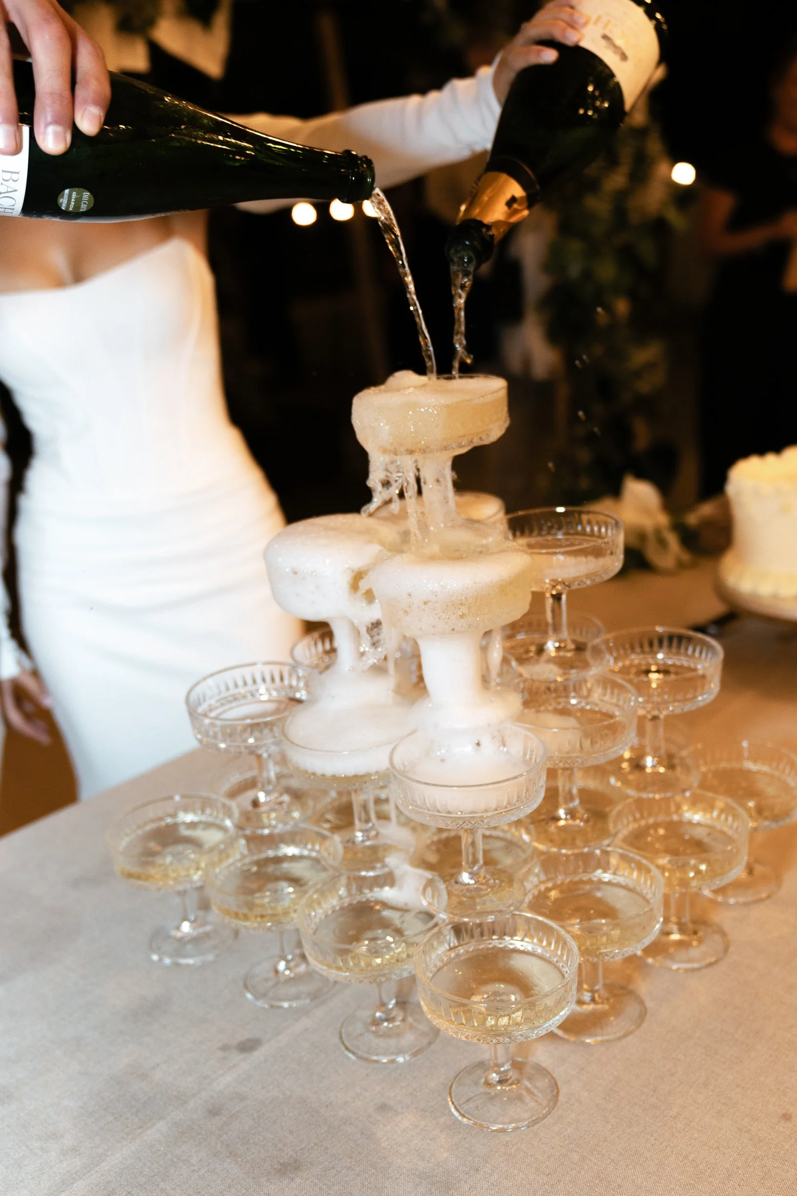 People pouring champagne into a tower of glasses at a celebration or party.