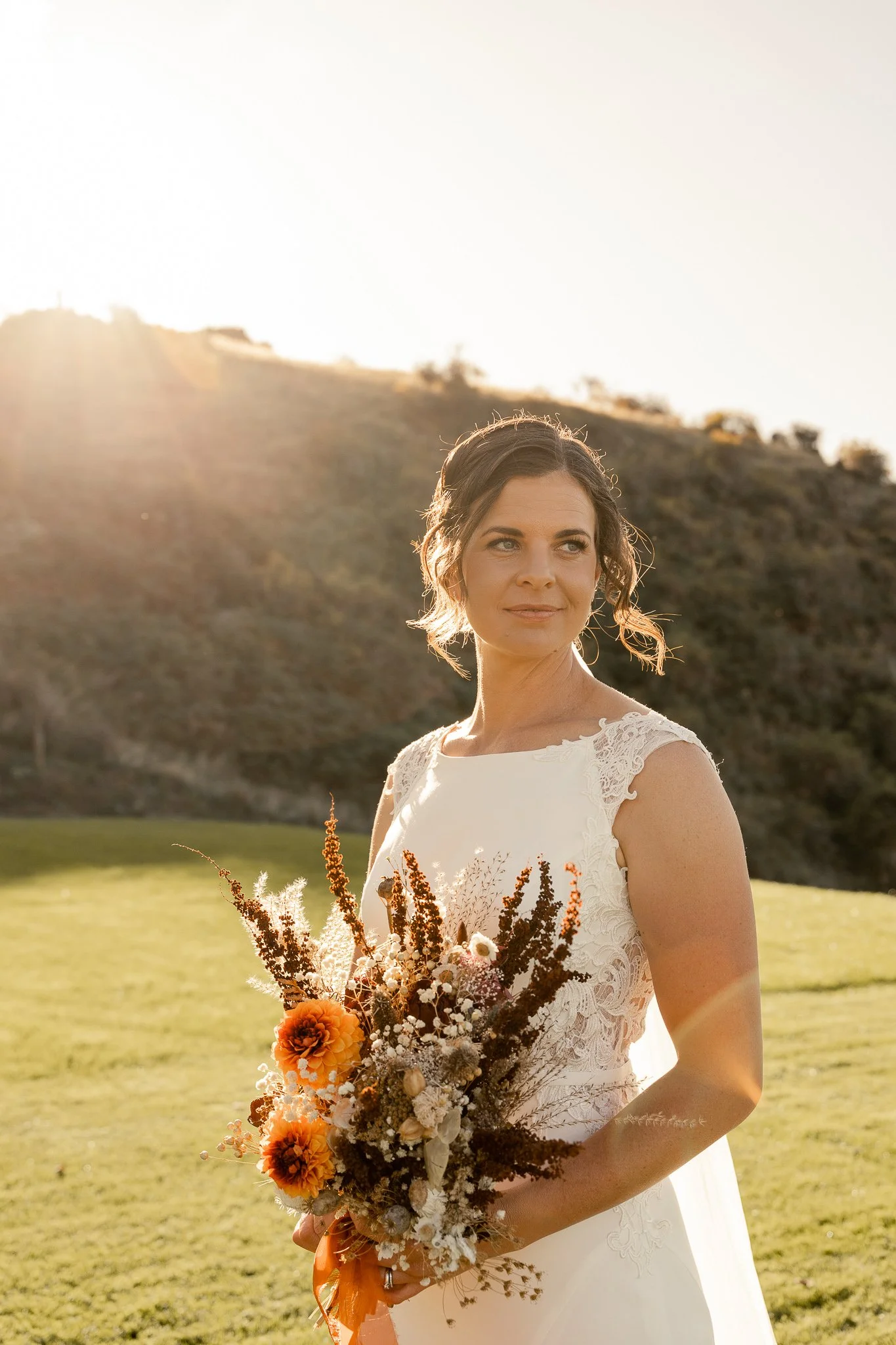 A bride holding her bouquet at sunset.