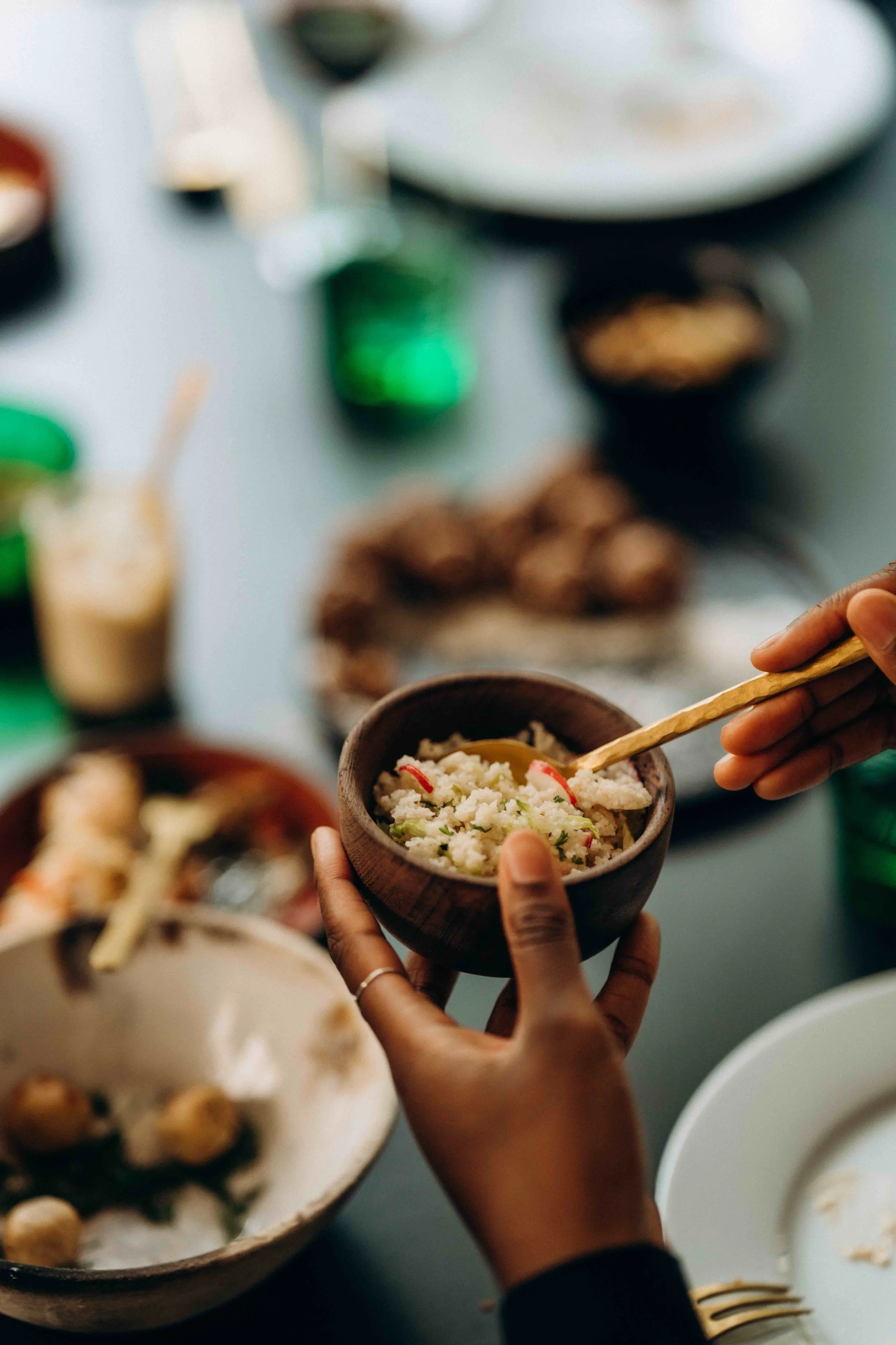 a bowl of fonio salad lifted of table with other foods