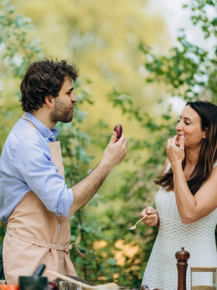 2 people talking to each other. one person holds a safou fruit