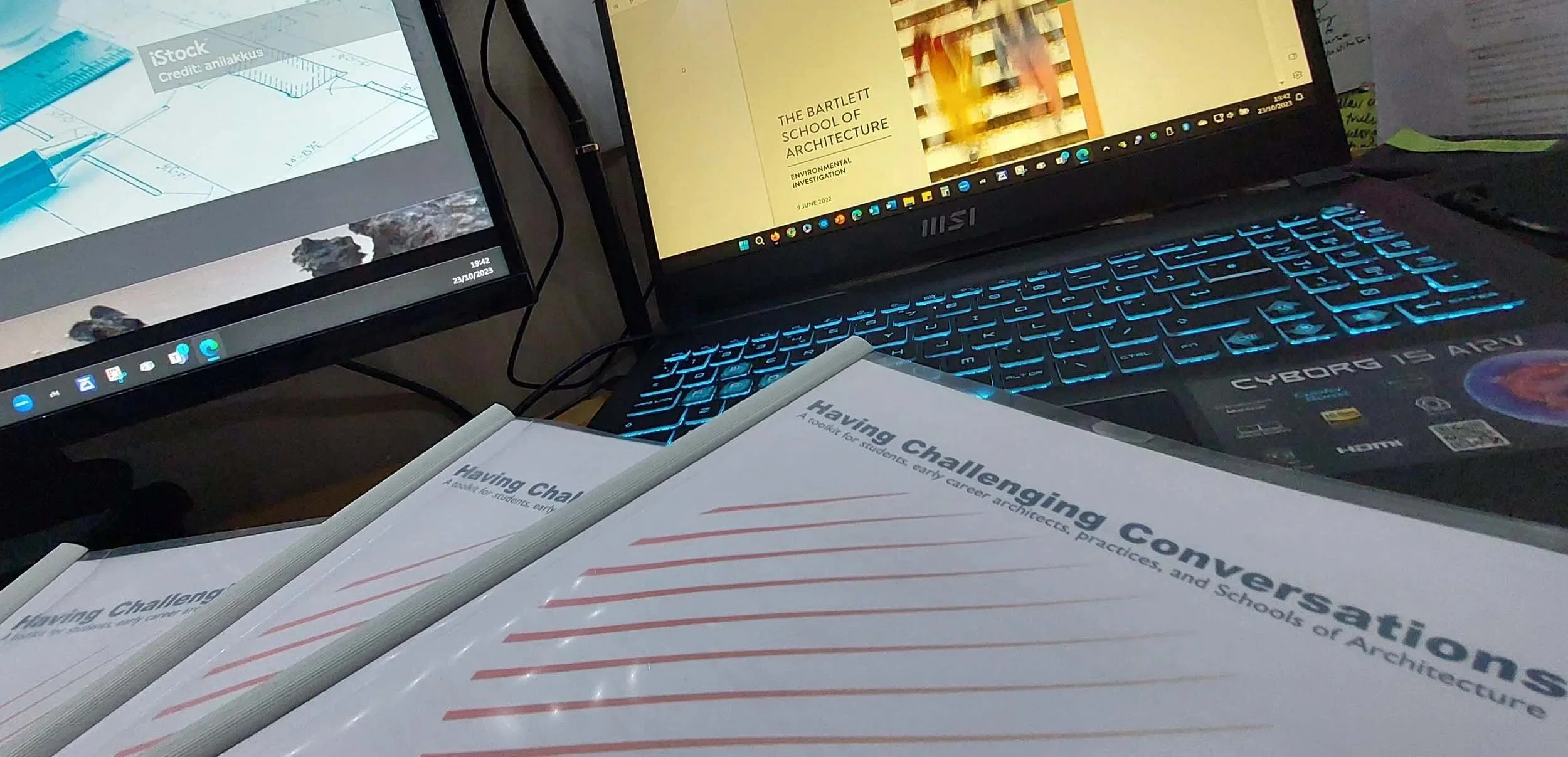 Printed “Having Challenging Conversations” toolkits beside a laptop and monitor, representing digital learning and inclusion training.