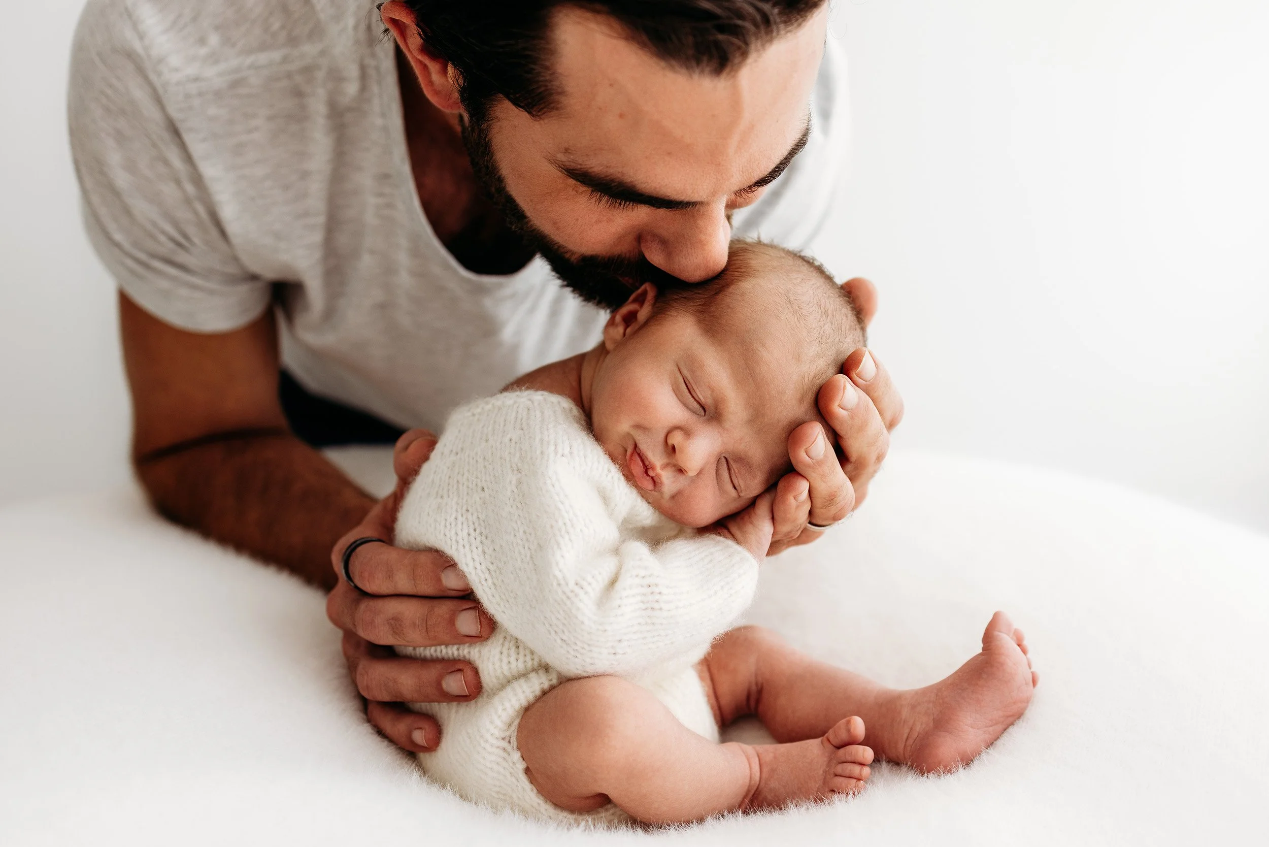 Parents looking lovingly at their newborn baby during a relaxed studio newborn session in Perth.