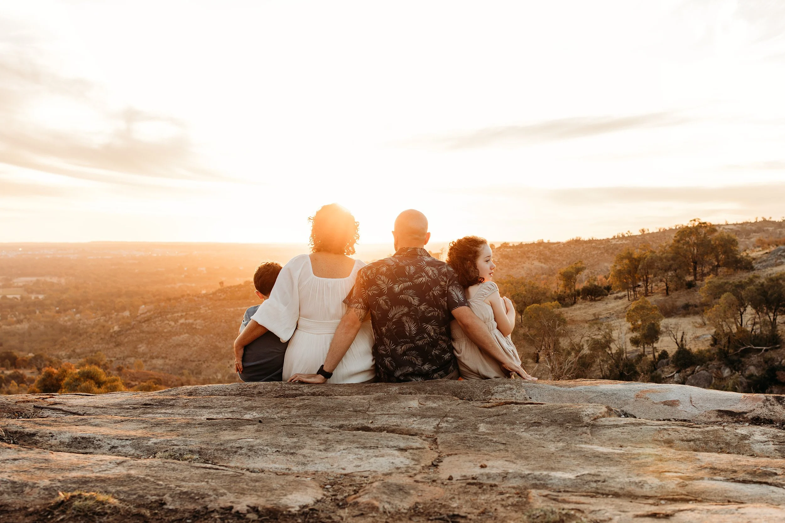 Family sitting together overlooking the landscape during a golden sunset photography session in Perth.