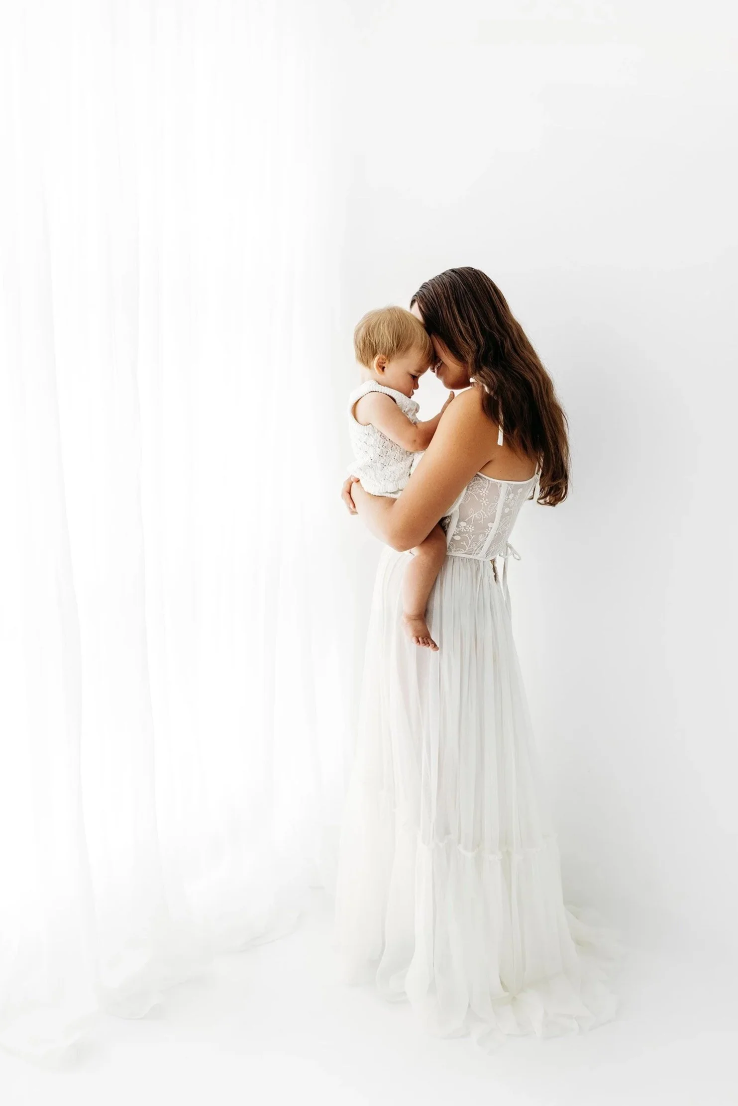 Mum standing and cuddling her baby in the light-filled Aveley studio