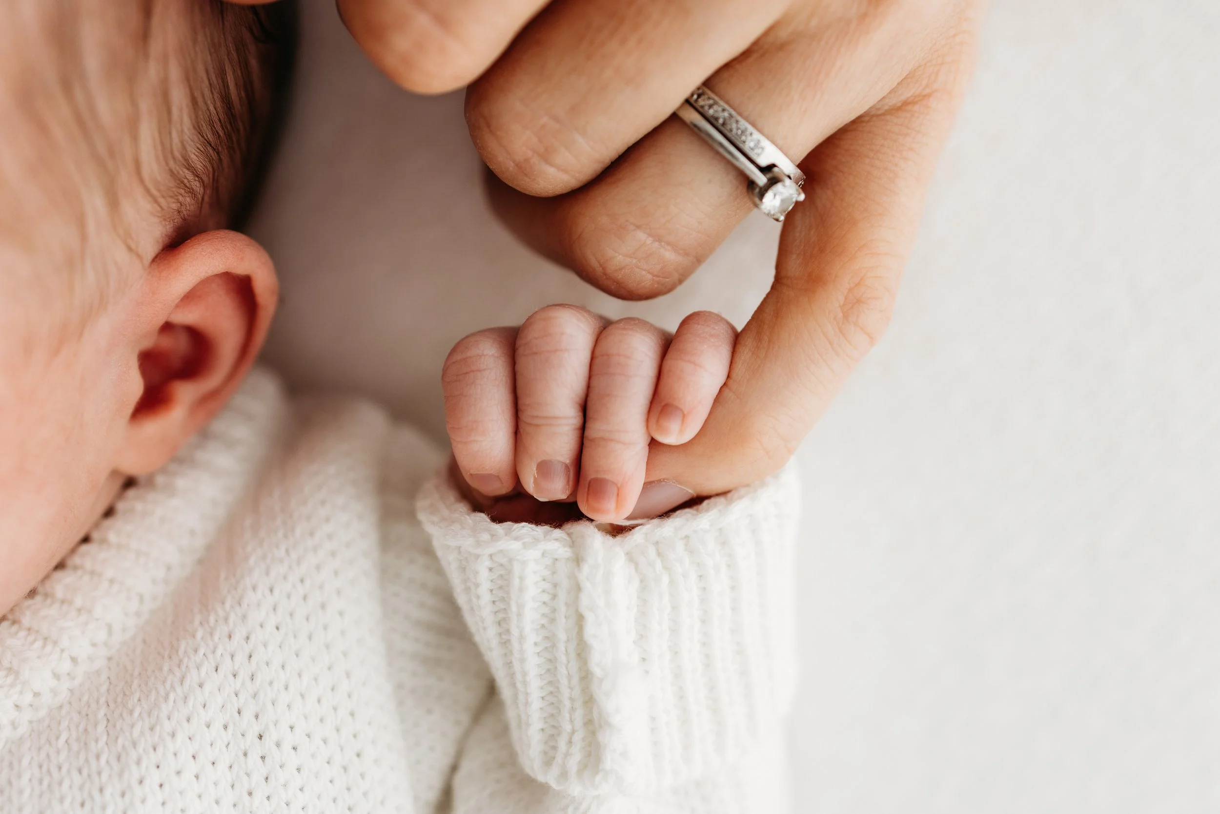 Close-up of a newborn baby holding Mum’s finger during a newborn photography session in Perth.