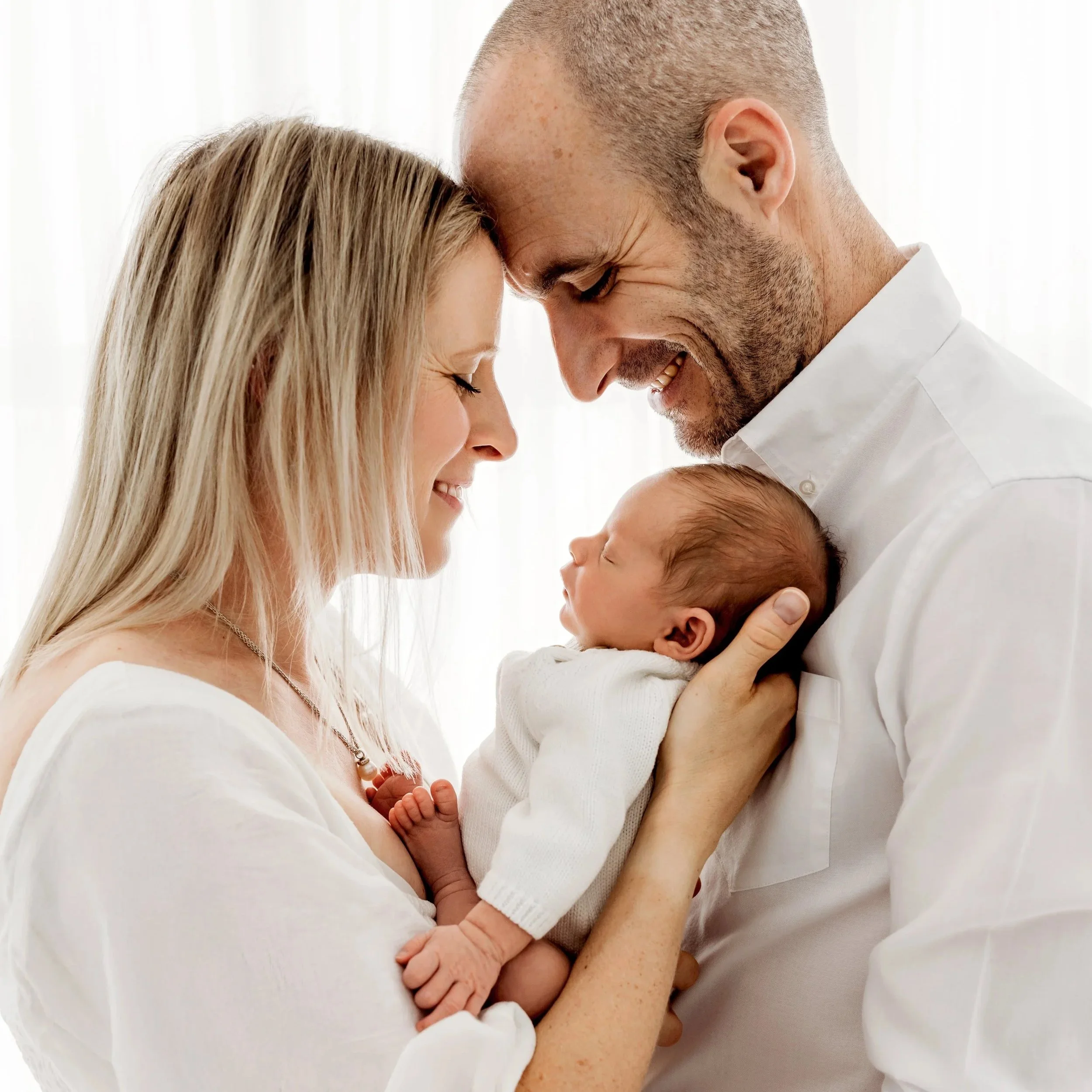 Newborn baby cuddled with their family during a relaxed studio photography session in Aveley, Perth.