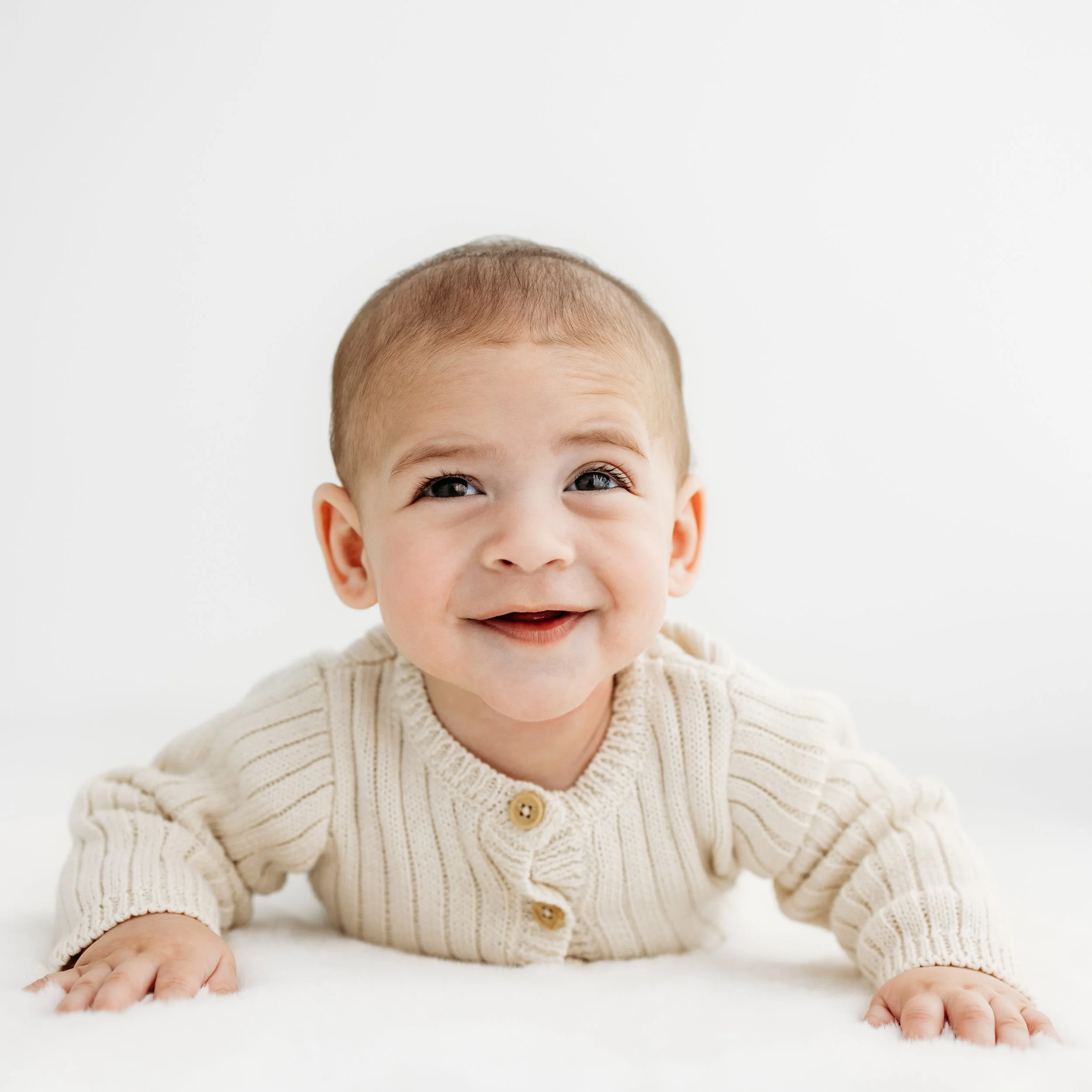 Smiling baby enjoying tummy time during a relaxed baby photography session in Perth.