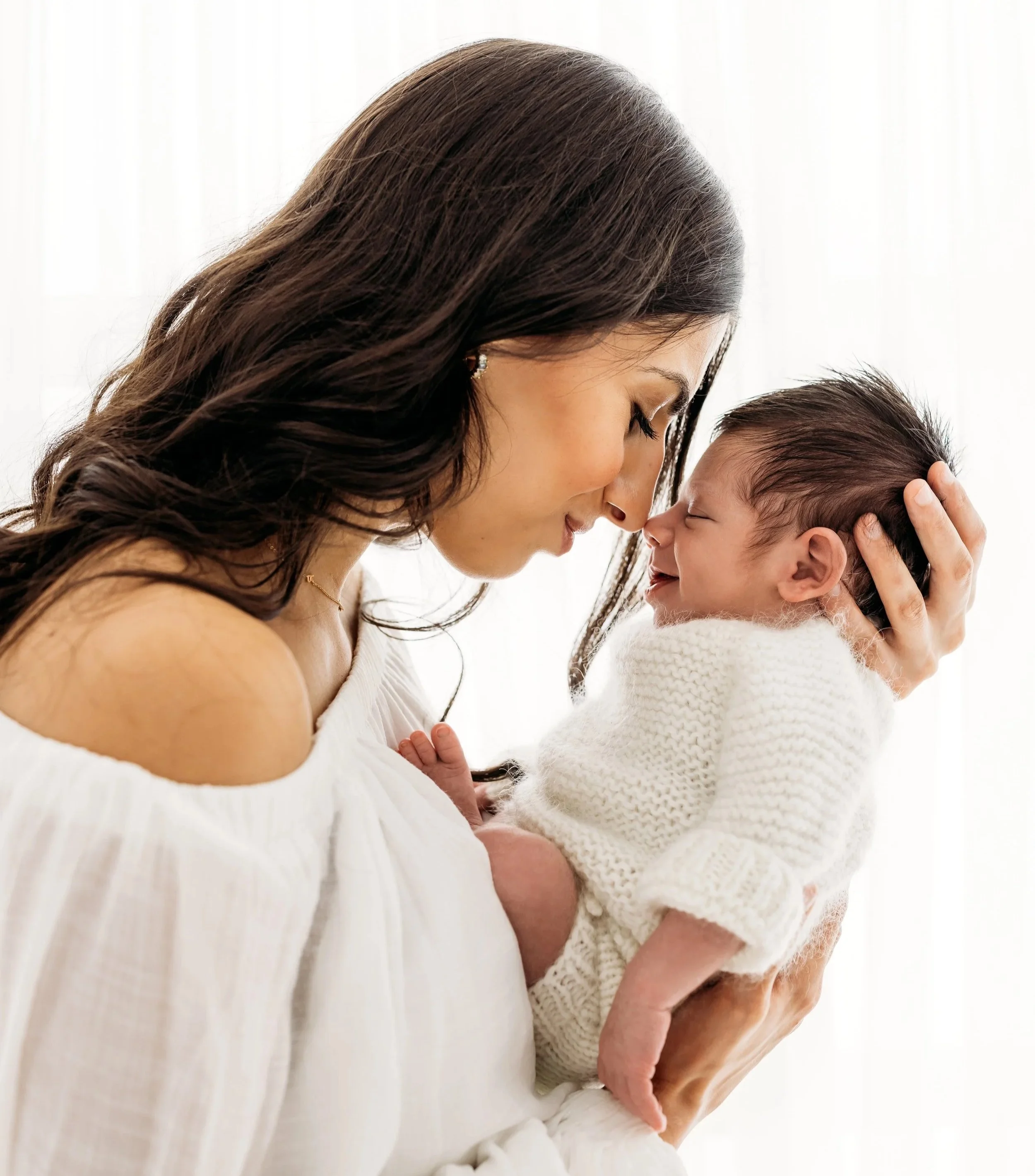 Mother cuddling her newborn baby during a relaxed studio photography session in Aveley, Perth.