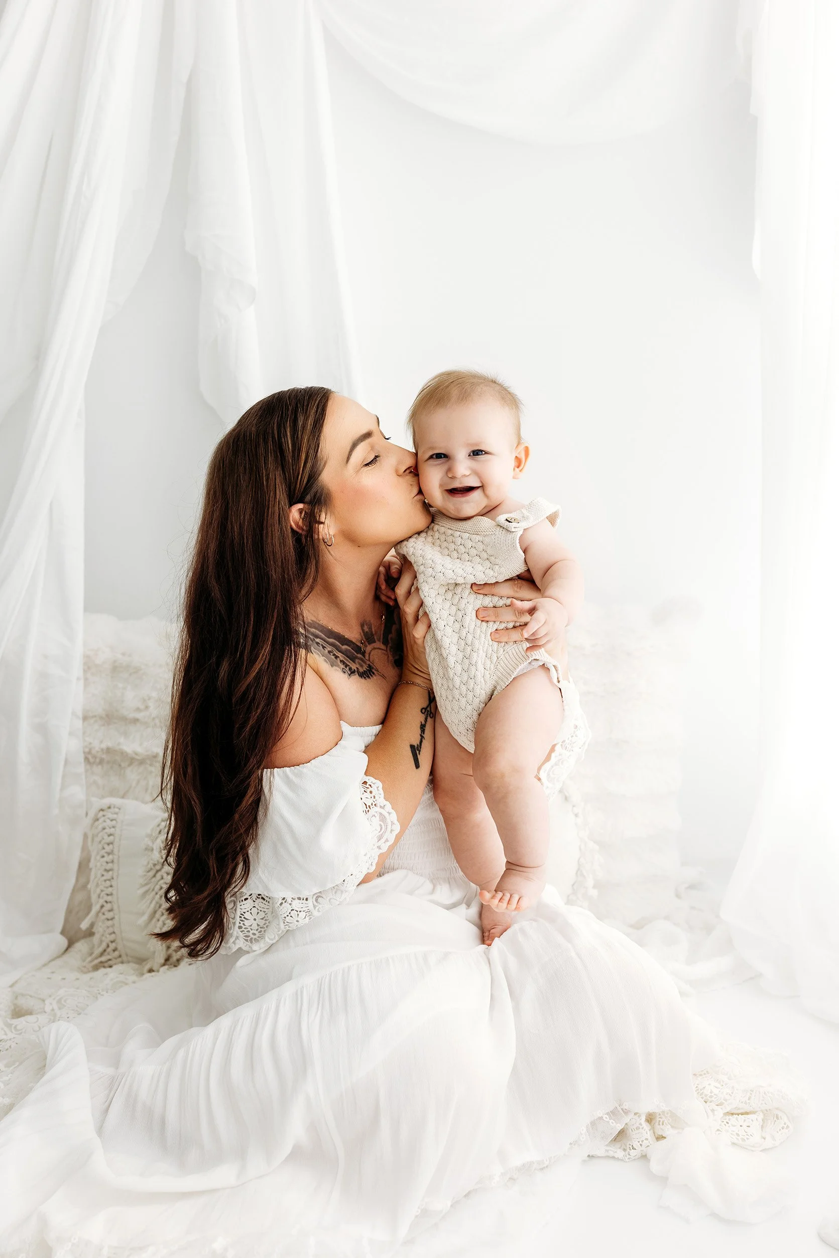 Mum kissing her smiling baby in the Love Olive Photography studio