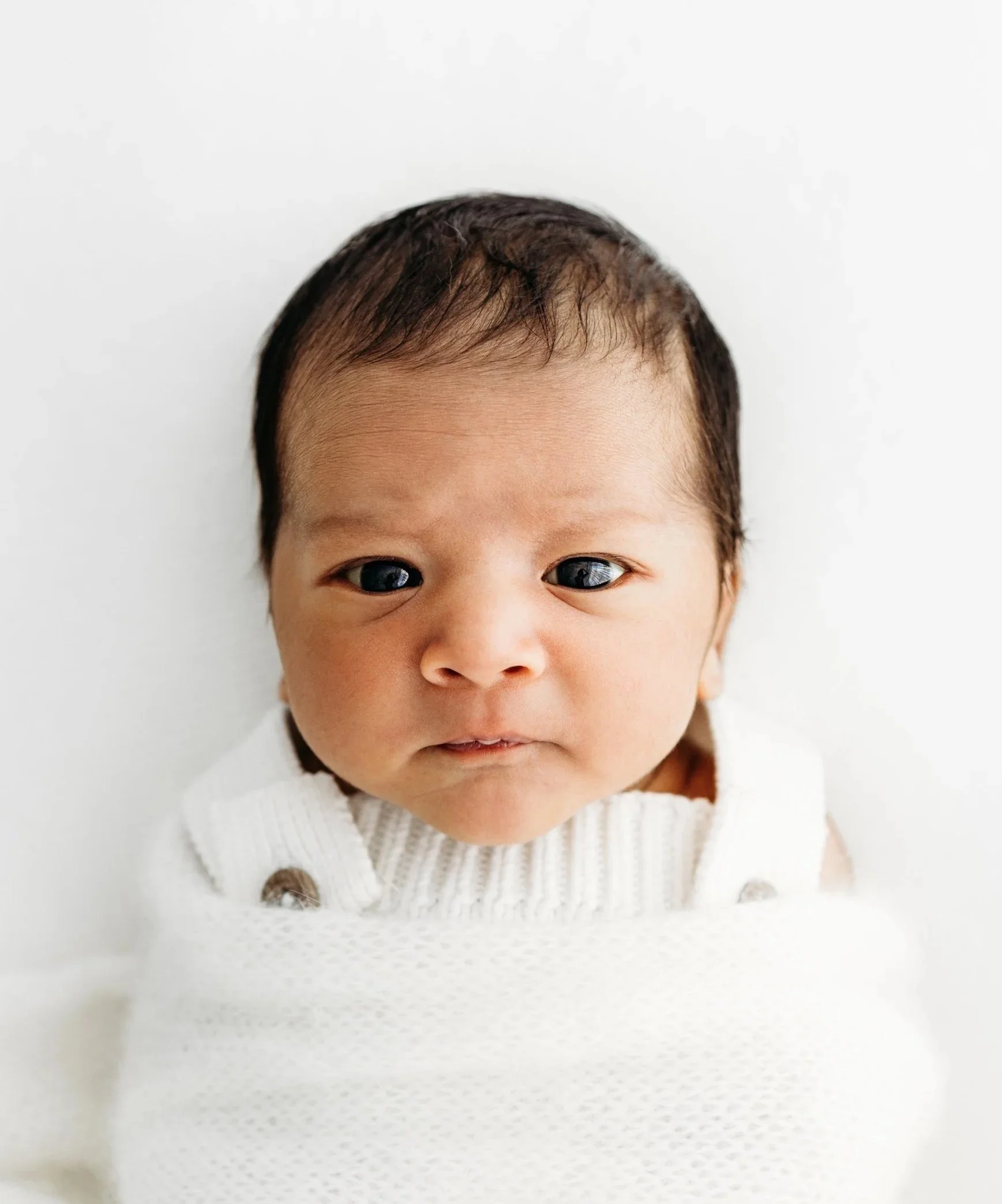 Awake newborn baby photographed in soft neutral tones at a Perth newborn photography studio.