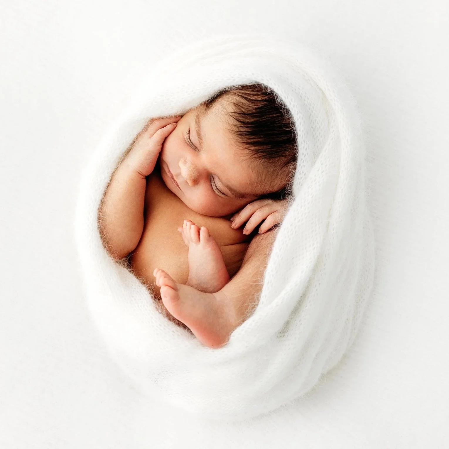 Newborn baby curled up in a white wrap during a newborn photography session in the Swan Valley, Perth.