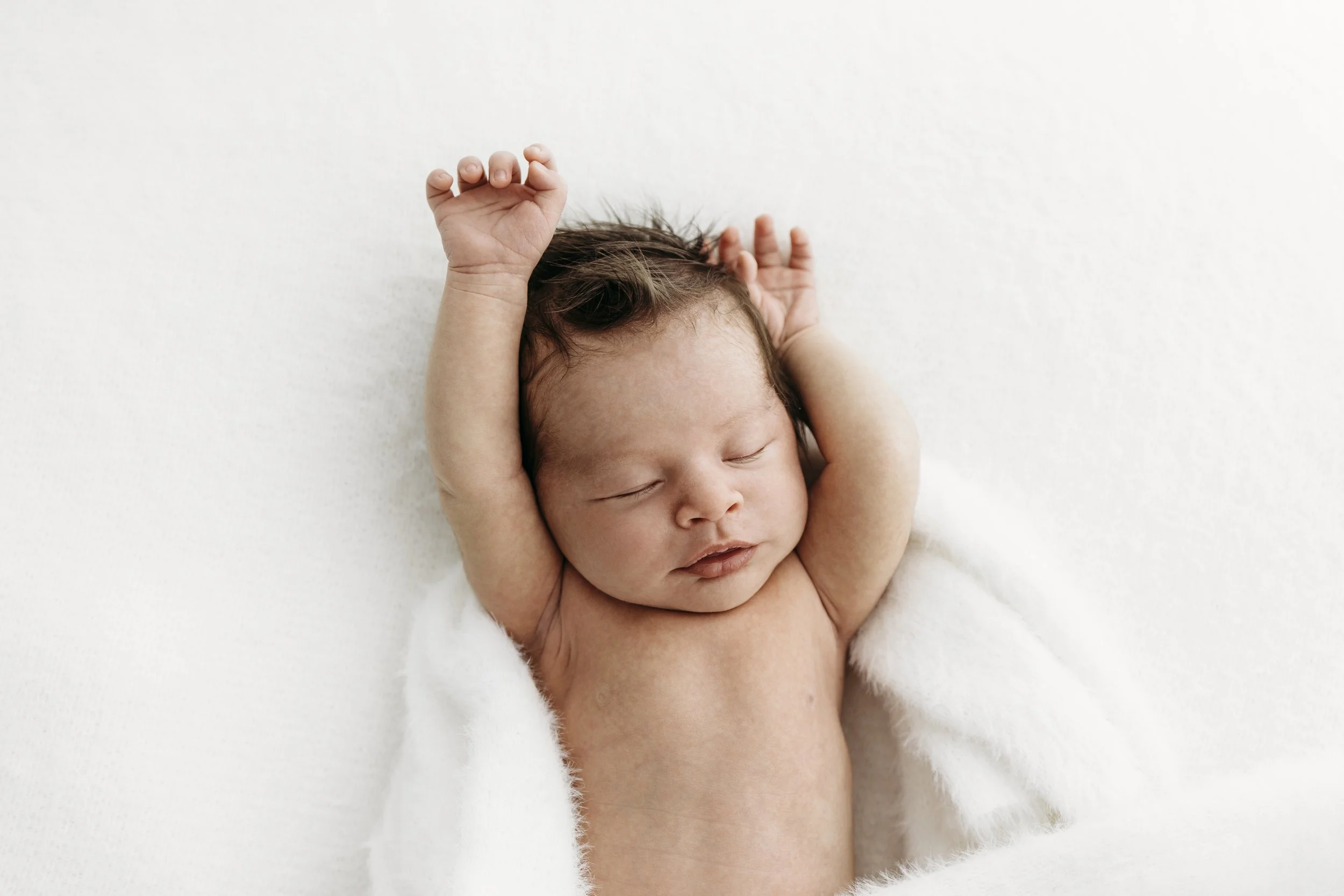 Newborn baby stretching naturally during a gentle, baby-led photography session in Perth.