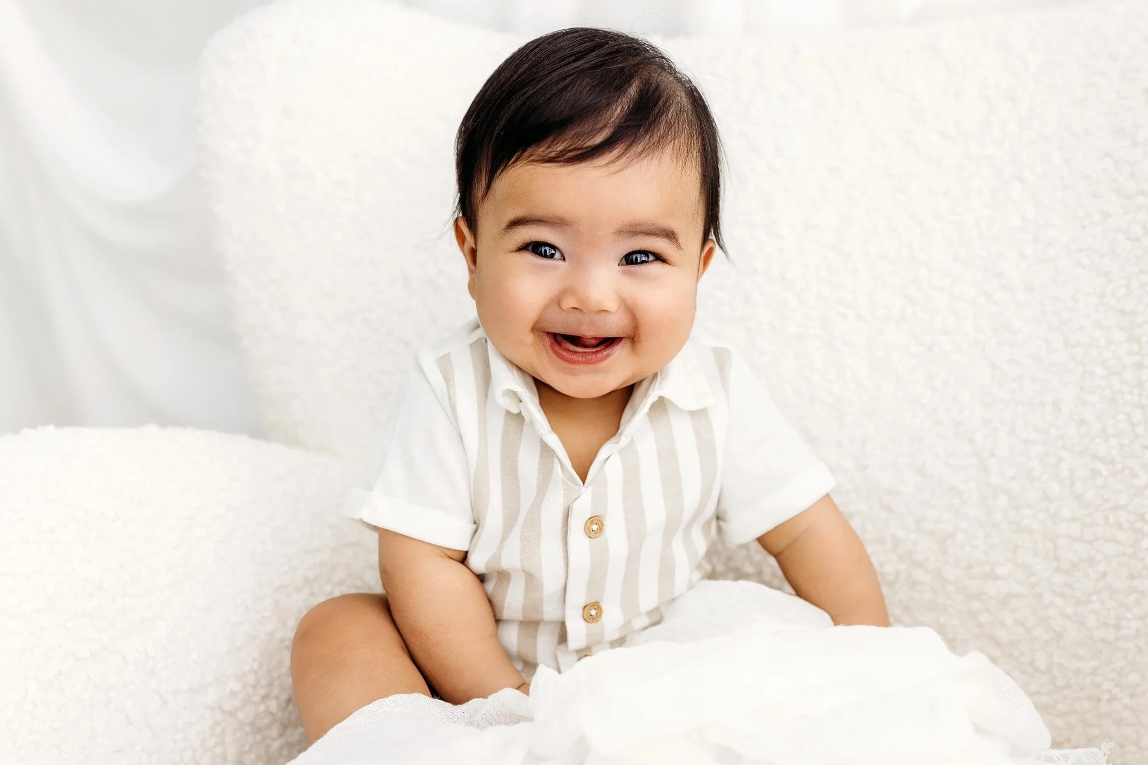 Smiling baby sitting independently during a milestone portrait session in Perth.