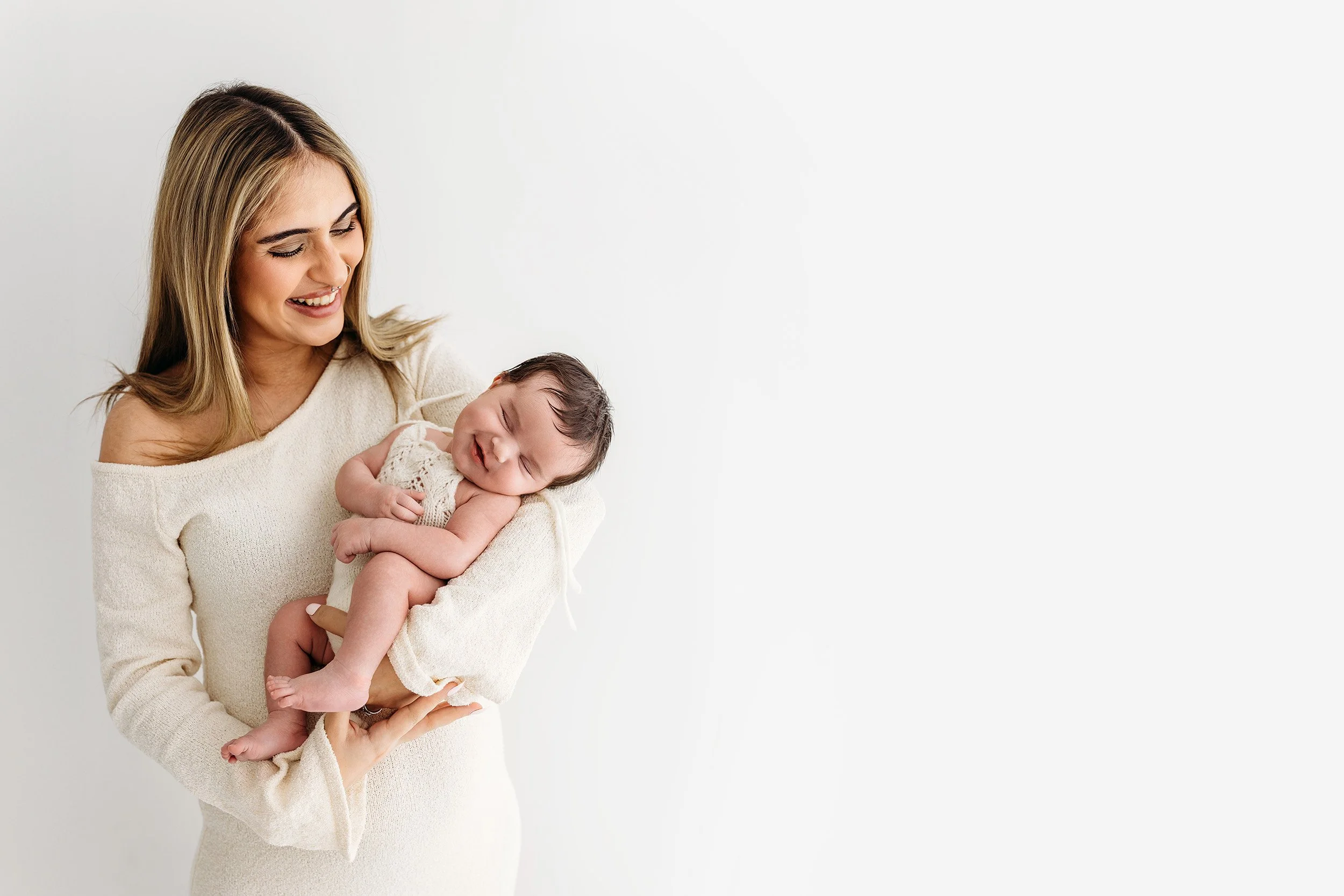 New mum smiling down at her newborn baby during a timeless studio newborn session.