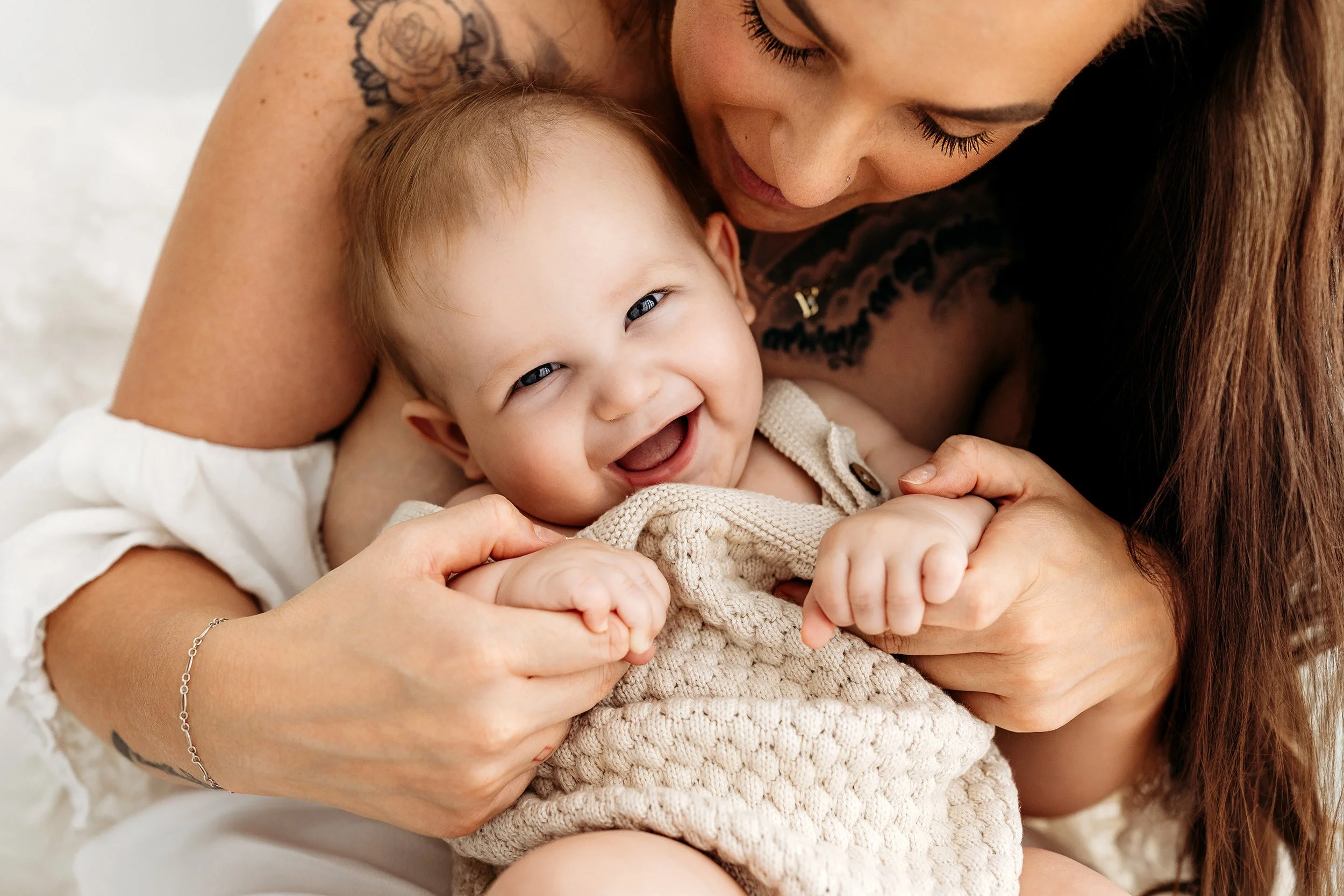 Mum cuddling her smiling baby during a studio photography session